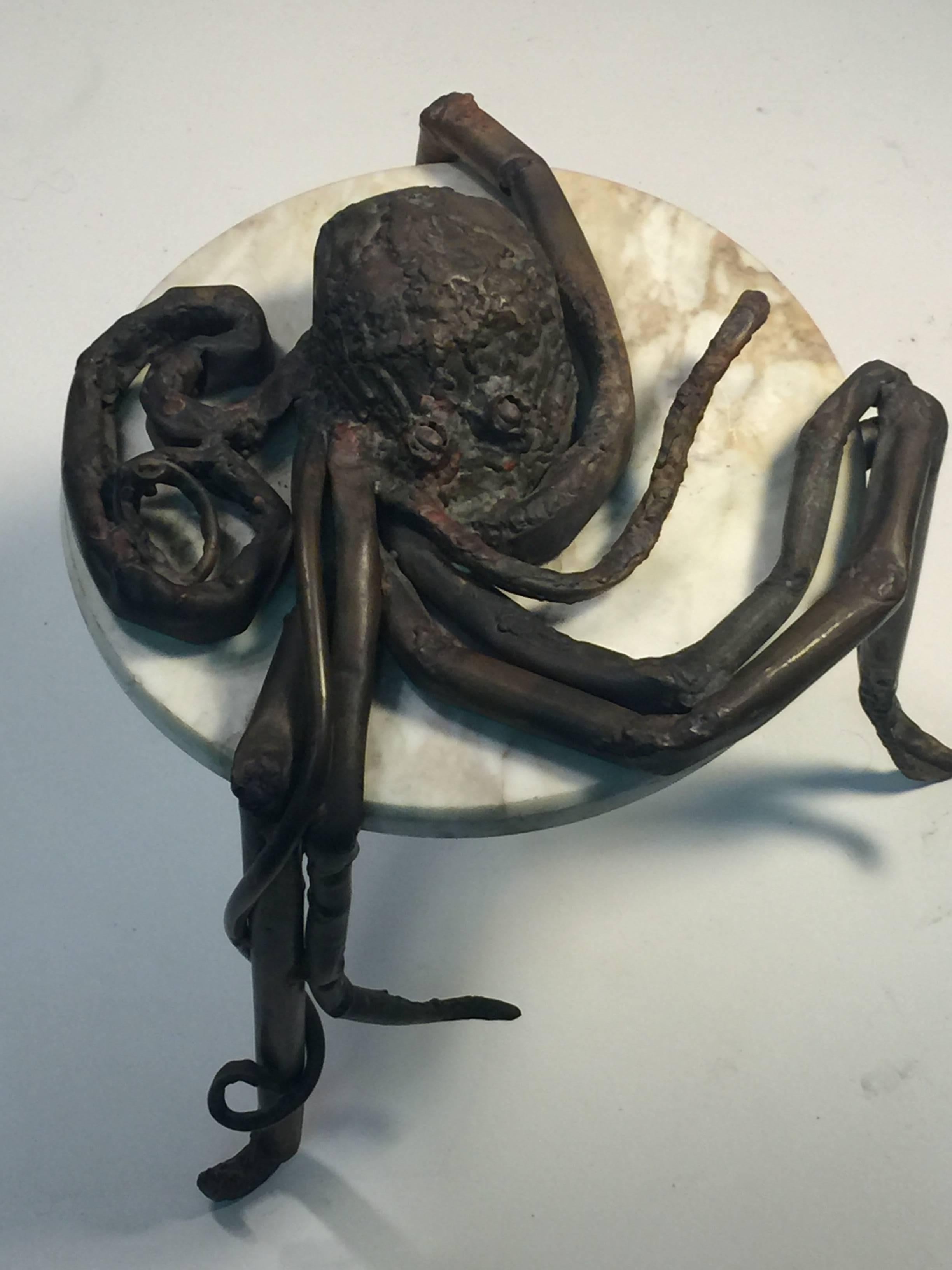 Hand-sculpted and forged metal octopus created in the Brutalist manner in the 1960s. Set with a round white and tan veined marble top. The marble is 3/4