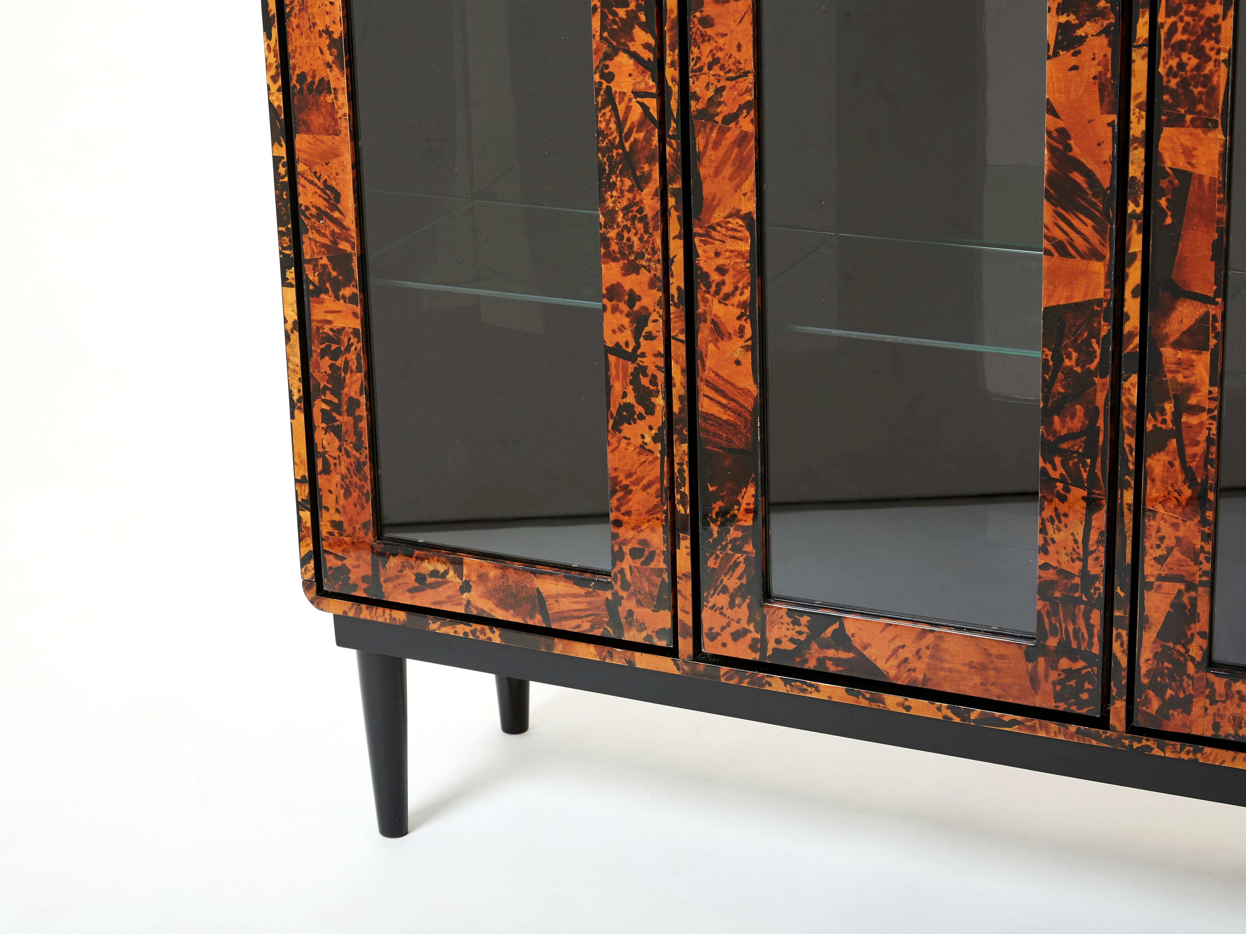 This unique Mid-century vitrine cabinet, made from solid oak covered by real tortoise shells fully varnished, was made in Milano by a small design studio called Ottini in 1973. It features three transparent glass doors, with glass shelves inside.