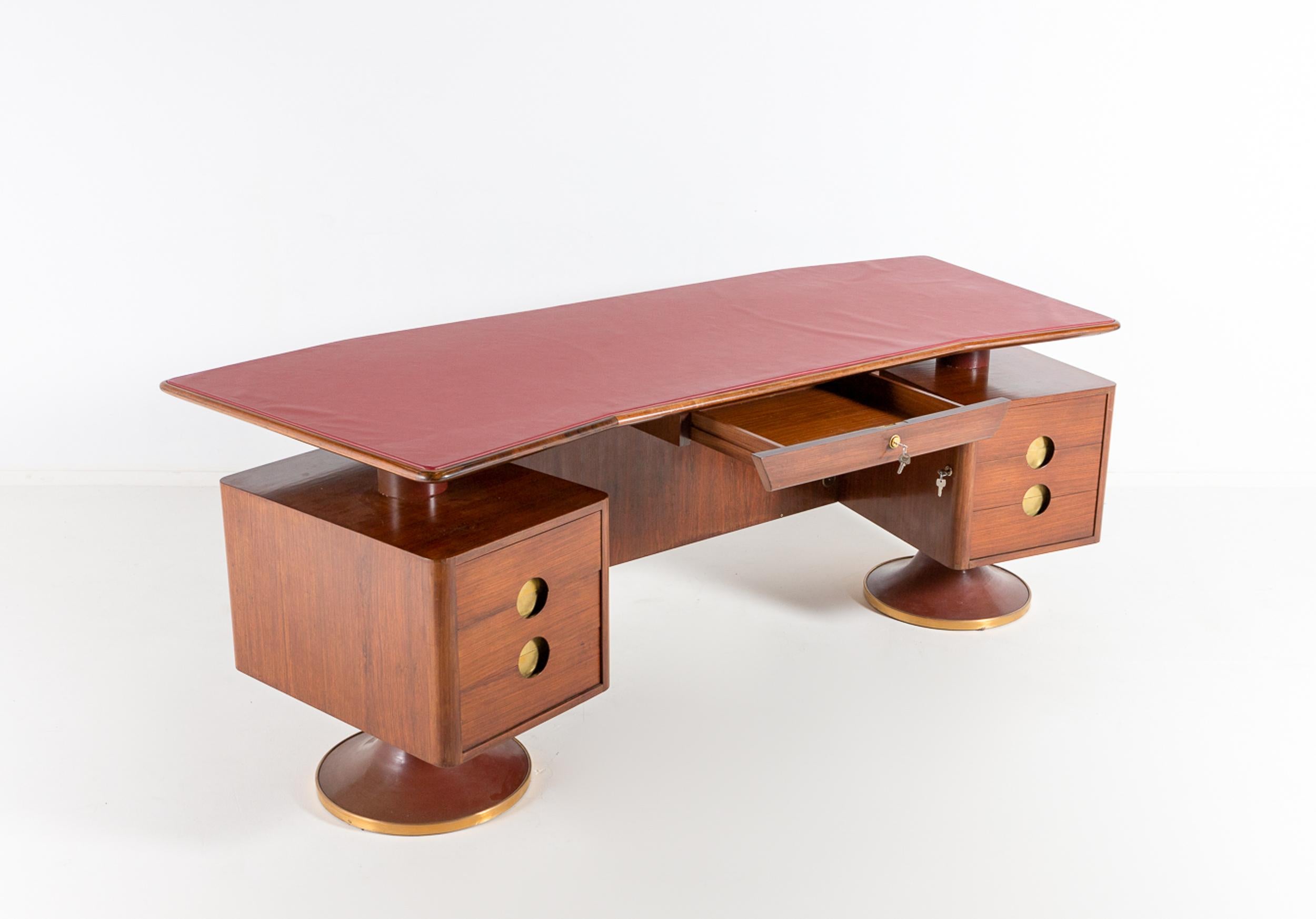 A superb Italian walnut and rosewood desk with matching rosewood and leather armchair, made to measure for the villa of an Italian executive in 1960. The floating boomerang shaped top is covered with the original red leather. The front of the desk