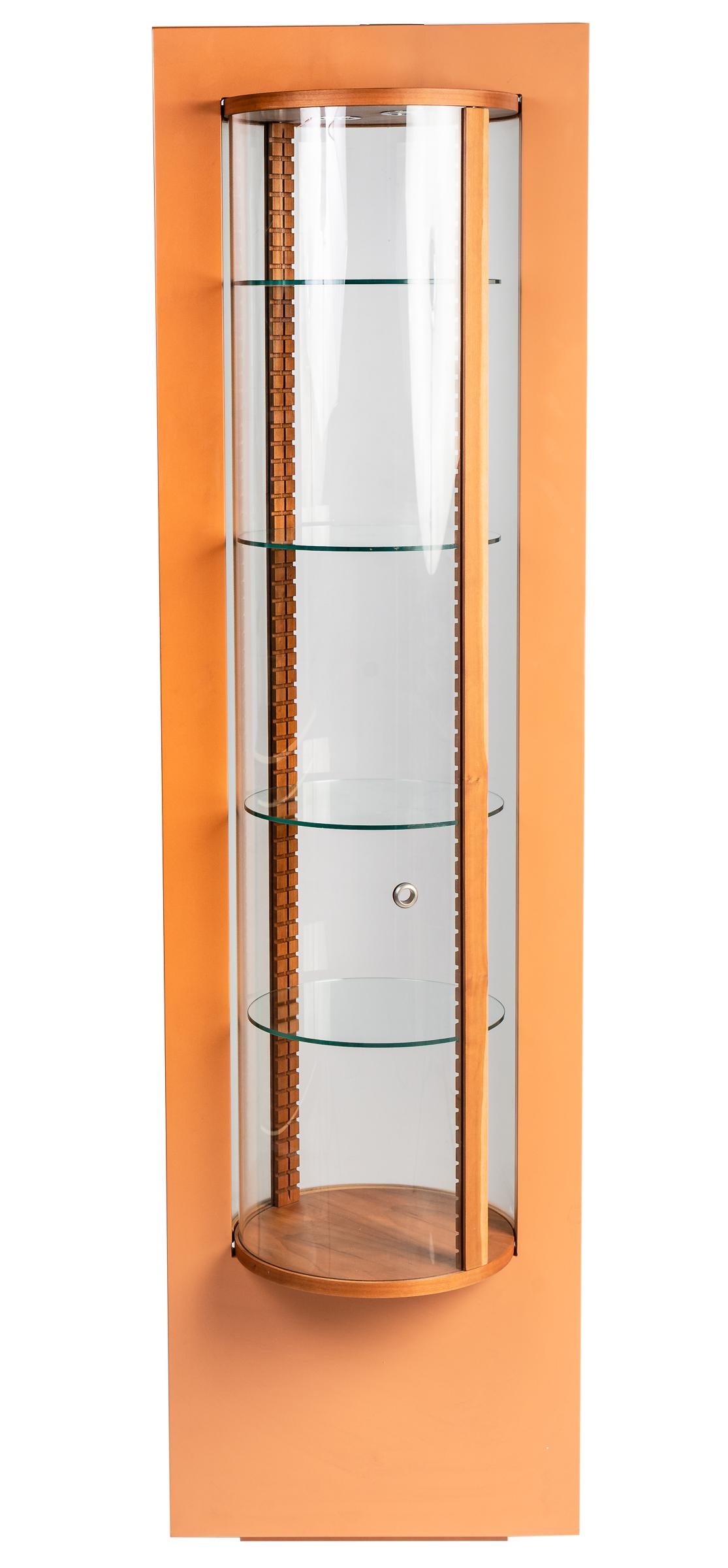 This beautiful illuminated display cabinet reveals the special design of Chr. Robert. The rounded glass panels turn in and can be opened in that way. The wooden structure gives the lighted glass cabinet a surrounding and the round glass shelves can