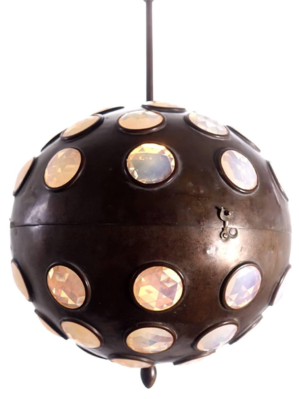 We have never seen another example like this. The brass globe is a foot in diameter and contains about 50 jeweled inserts. The globe is hinged and splits open to change the bulb.