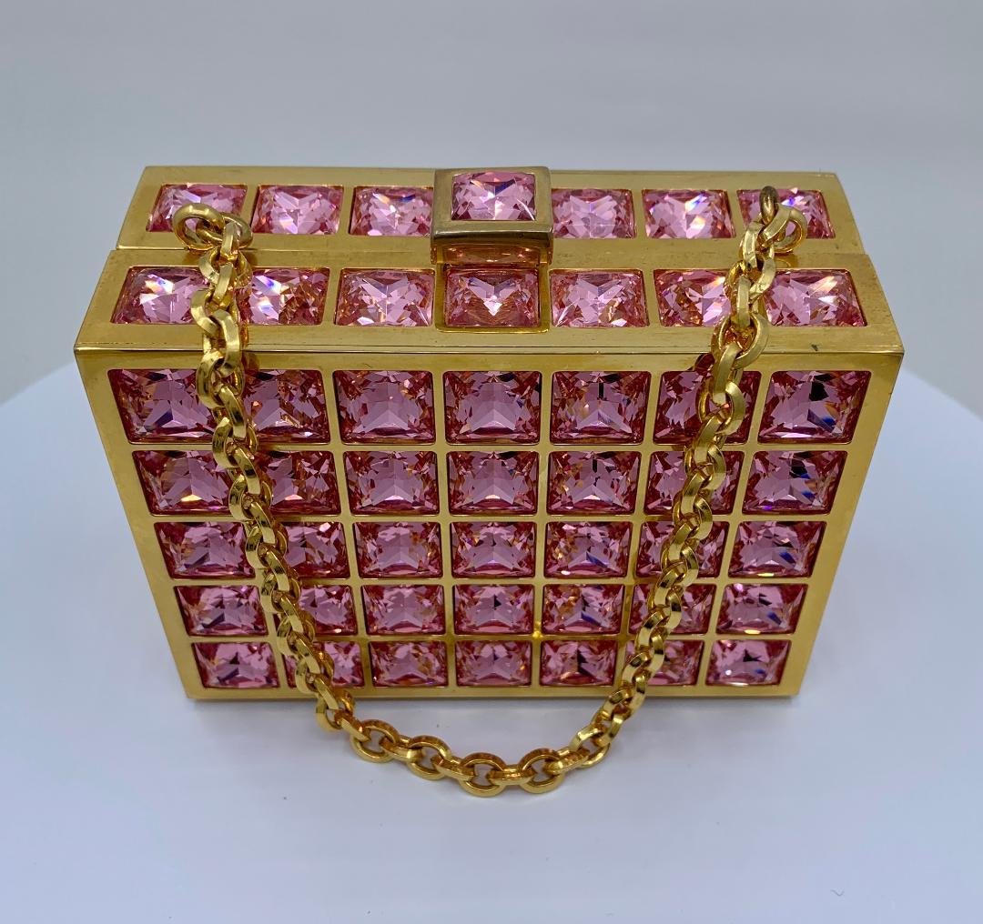 Exquisite handmade couture designer, Judith Leiber, crystal minaudiere evening bag is completely covered in pink square shaped crystals set between panels of square gold toned metal surrounds. Rich gold toned metal frame with metallic gold leather