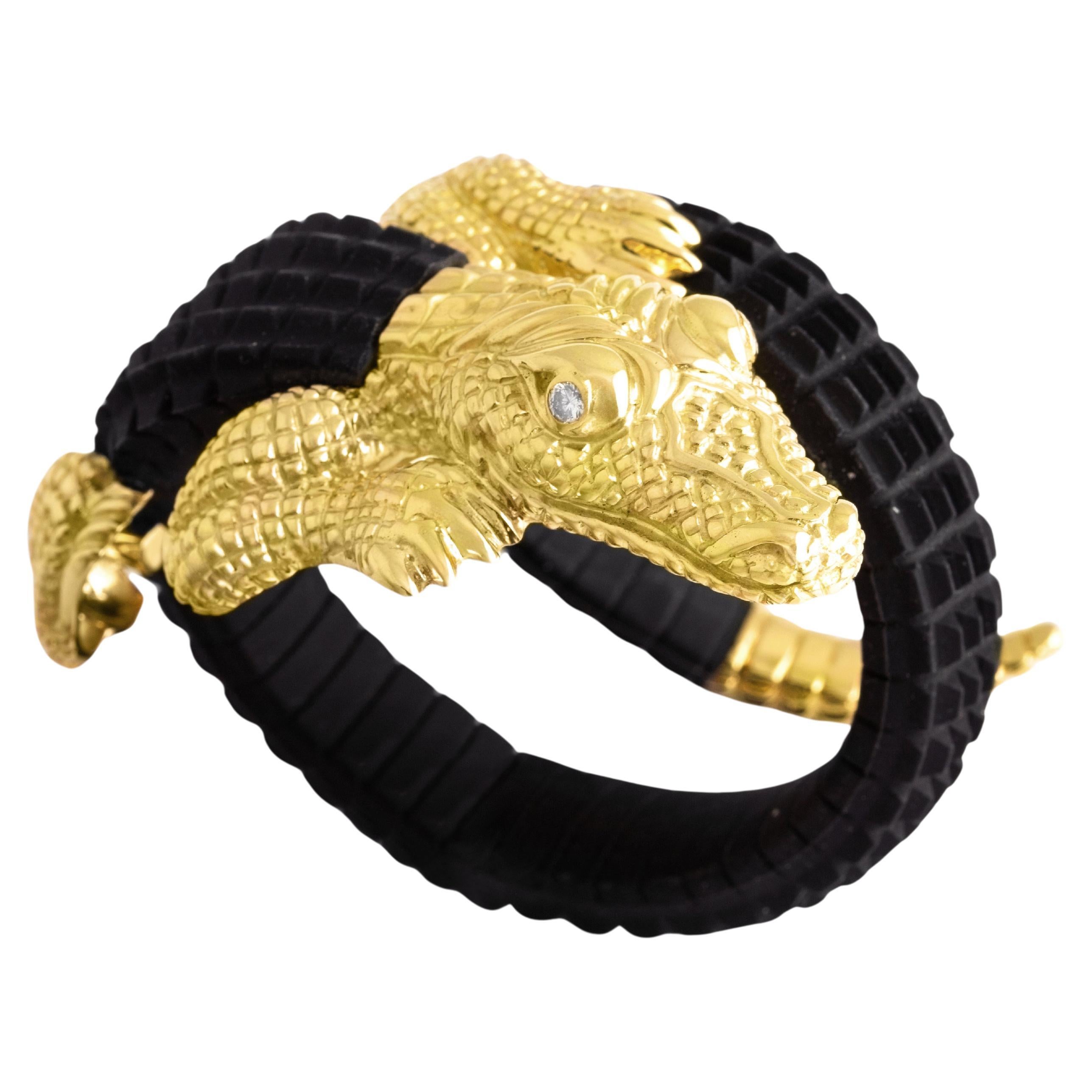 You will want to wrap this artfully sculpted creature around your wrist. Big, bold, and realistically rendered in 18K yellow gold and black rubber, this remarkable reptile has a satiny finish with shimmering highlights. 
The eyes are set with