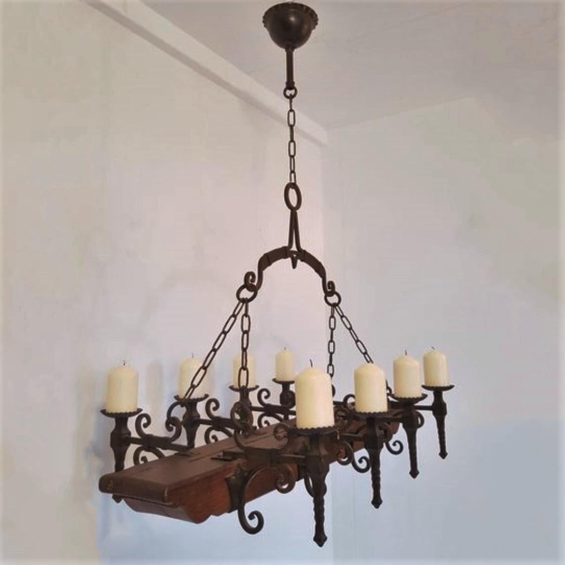 Unique handcrafted forged wrought iron and oak castle candle chandelier, Spain, mid-19th century.
Wrought Iron beautifully forged in Medieval style, 8 candle holders on a rubust hand-carved oak horizontal piece. 
A great eye-catcher above a long
