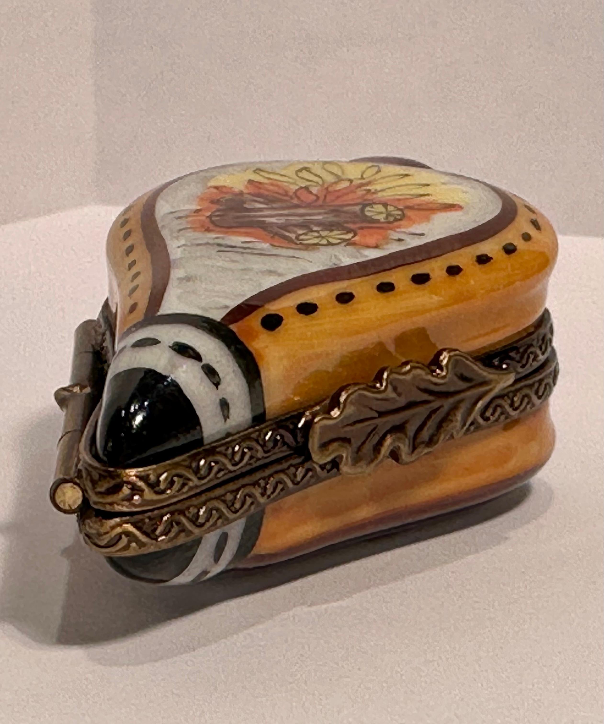 Collectible and very unique, Limoges porcelain miniature trinket box is handmade and hand painted in France and features a very detailed bellows with a hand-painted burning logs scene on one side and a hook and arrow scene on the reverse side. The