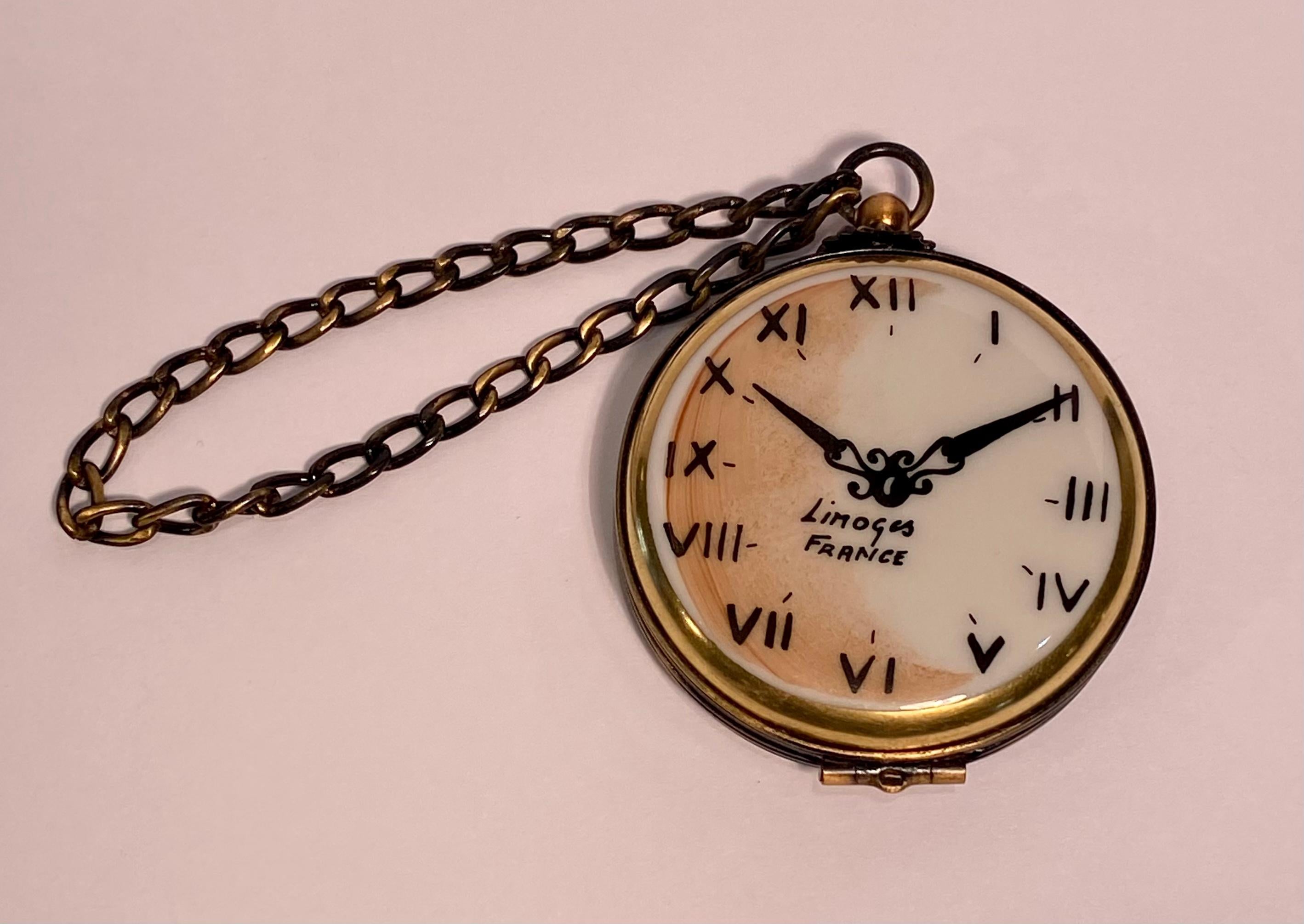 Collectible and very unique, Limoges porcelain miniature pocket watch look trinket box is handmade in France and features a hand painted watch face with Roman numerals and hands. Accenting the box on the top, is a hanging chain giving it a very