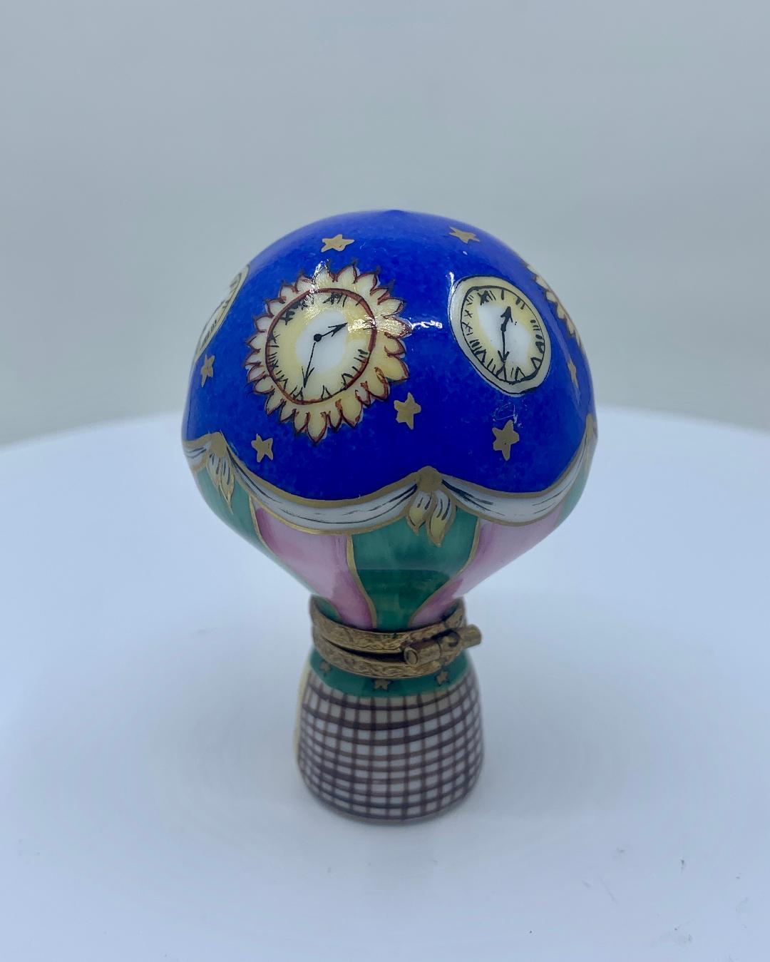 Collectible and unique, Limoges Rochard porcelain miniature trinket box is handmade and hand painted in France and features a very detailed vivid cobalt blue hot air balloon with celestial gold stars and four sun clocks interspaced between round