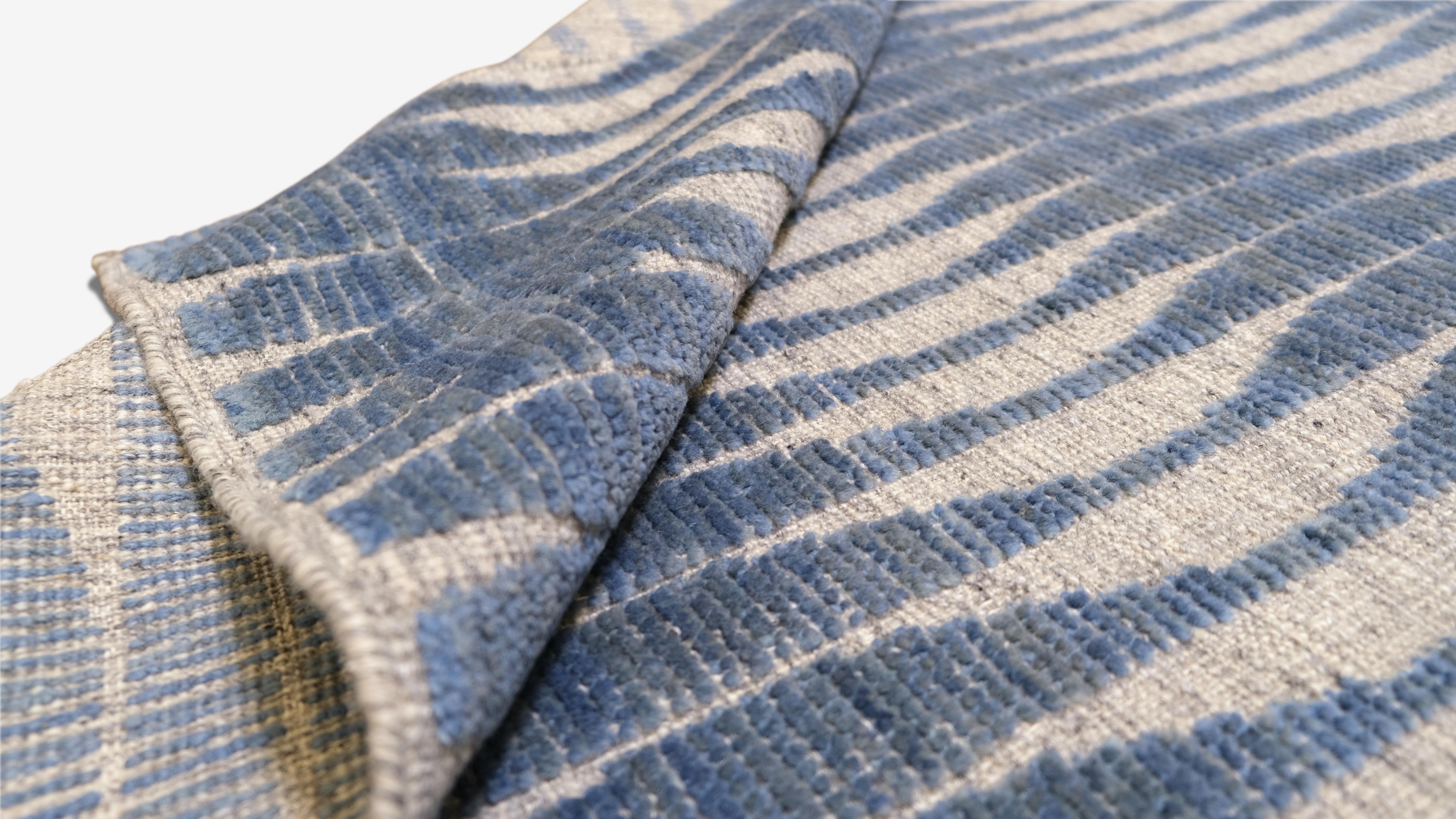 Add a touch of modern elegance to your space with this exquisite hand-knotted wool rug. Featuring a mesmerizing blue and light grey wave pattern, this rug introduces a sense of movement and fluidity to any interior. Perfect for contemporary or
