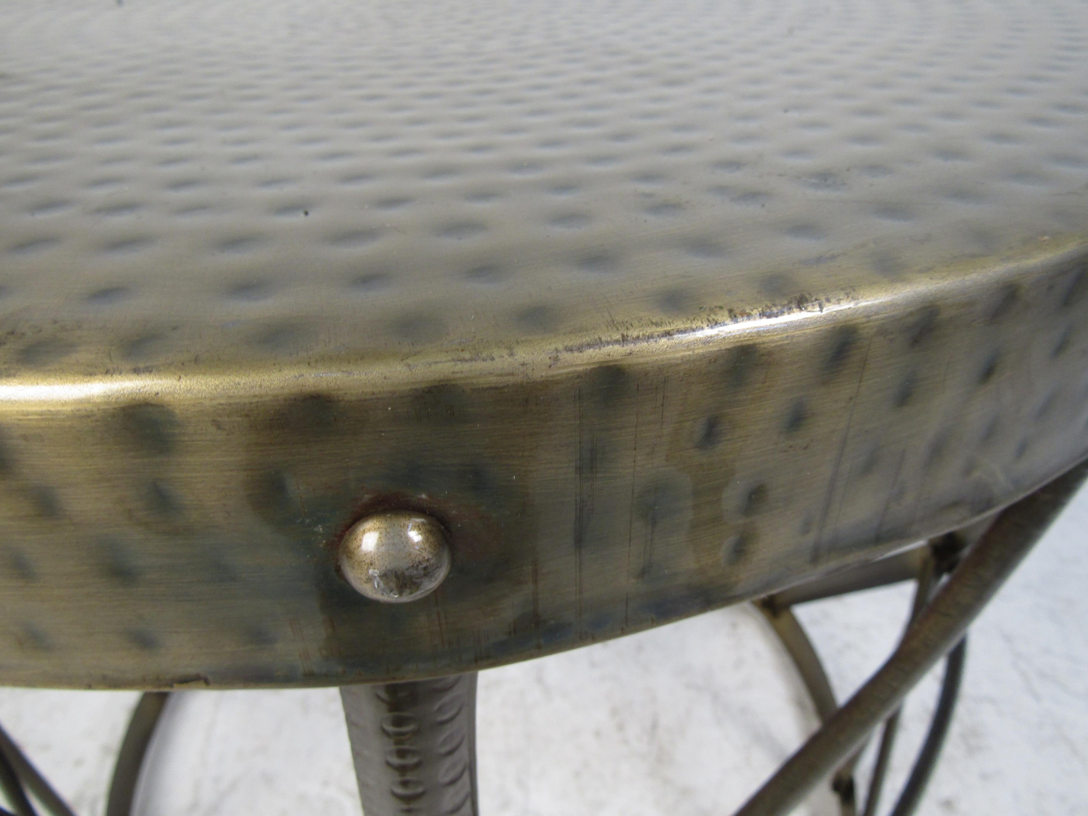 A round metal side table that features stretchers crossing each other along the base and a unique top with dimples. A wild design that looks great in any home, business, or office. Please confirm item location (NY or NJ).