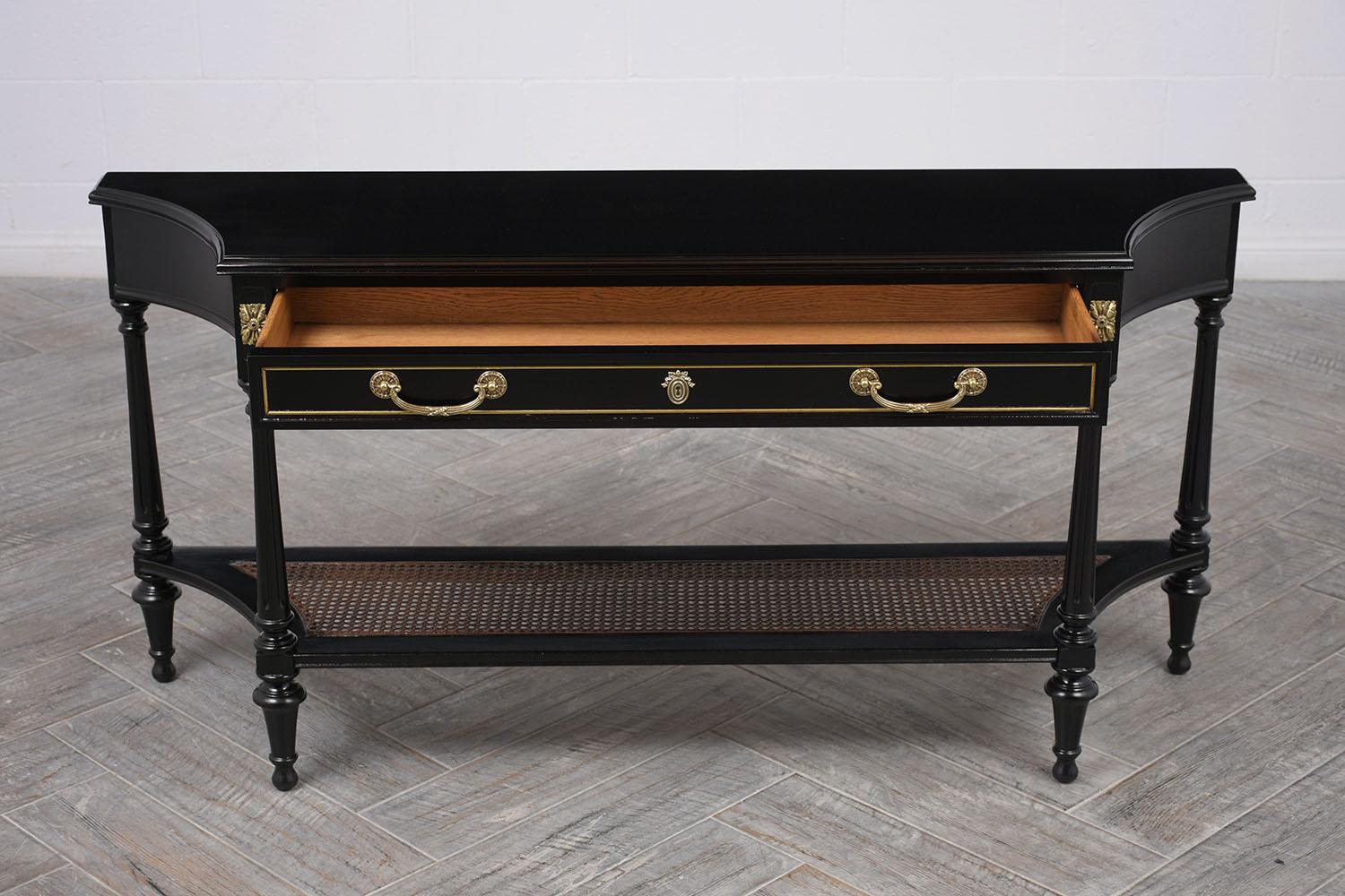 Beautiful 1950s console table in Hollywood Regency-style. Solid unique mahogany wood top with beveled trim. Single long front drawer with 2 brass handles and center keyhole and side brass floral decor. Followed by 4 lovely carved legs, finished with