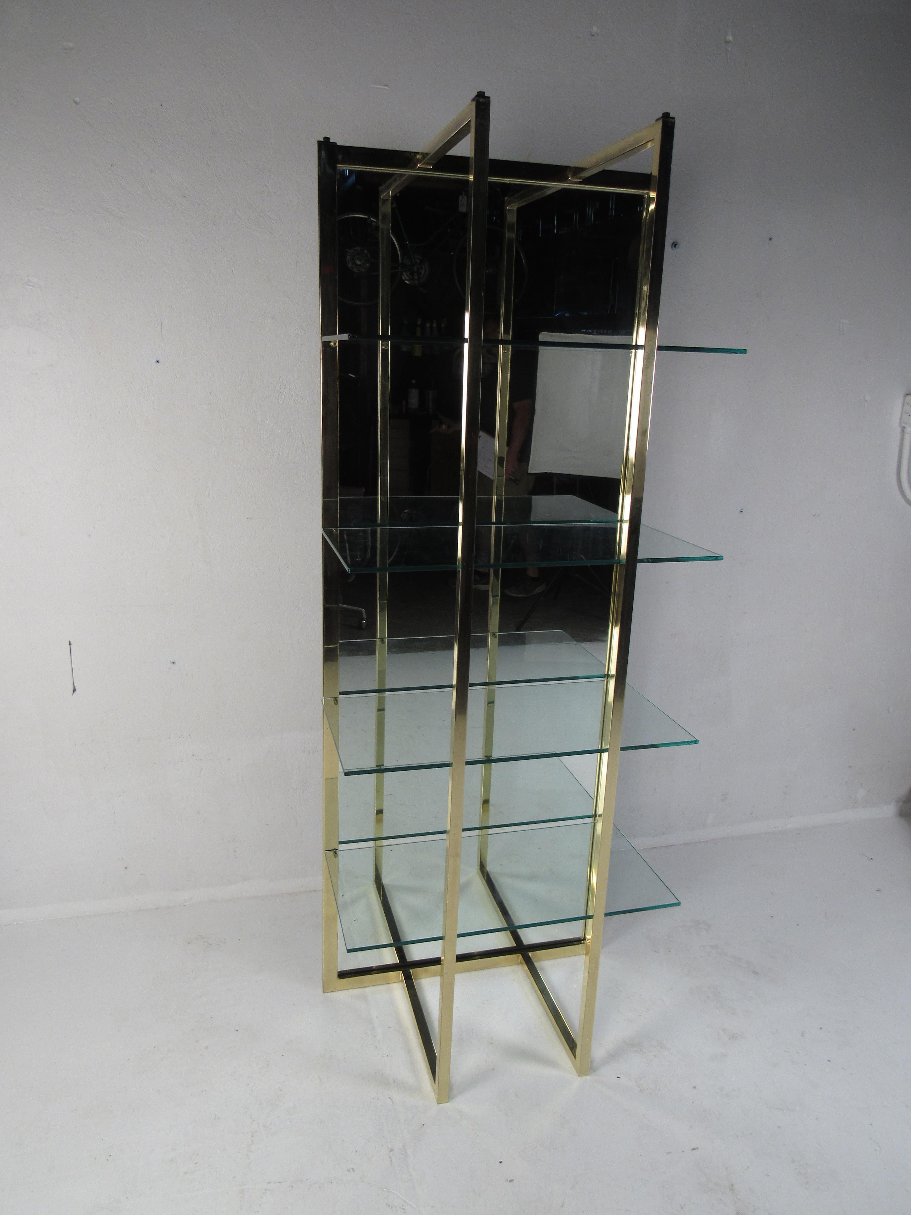 An elegant Hollywood Regency style design with a mirrored back, brass frame, and four large glass shelves. This beautiful vintage modern bookcase makes the perfect eye-catching addition to any home, business, or office. Please confirm the item