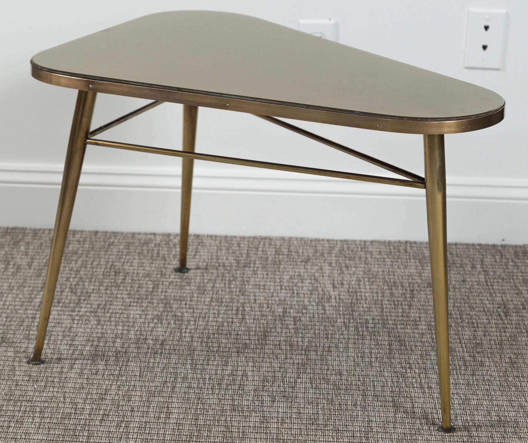 Wonderful Italian Design rounded right rectangular shaped table in solid unlacquered brass.  Table is shown with its original inset gold colored  glass top,. Brass table is joined with stretchers on three tapered and outstretched legs
Dating: