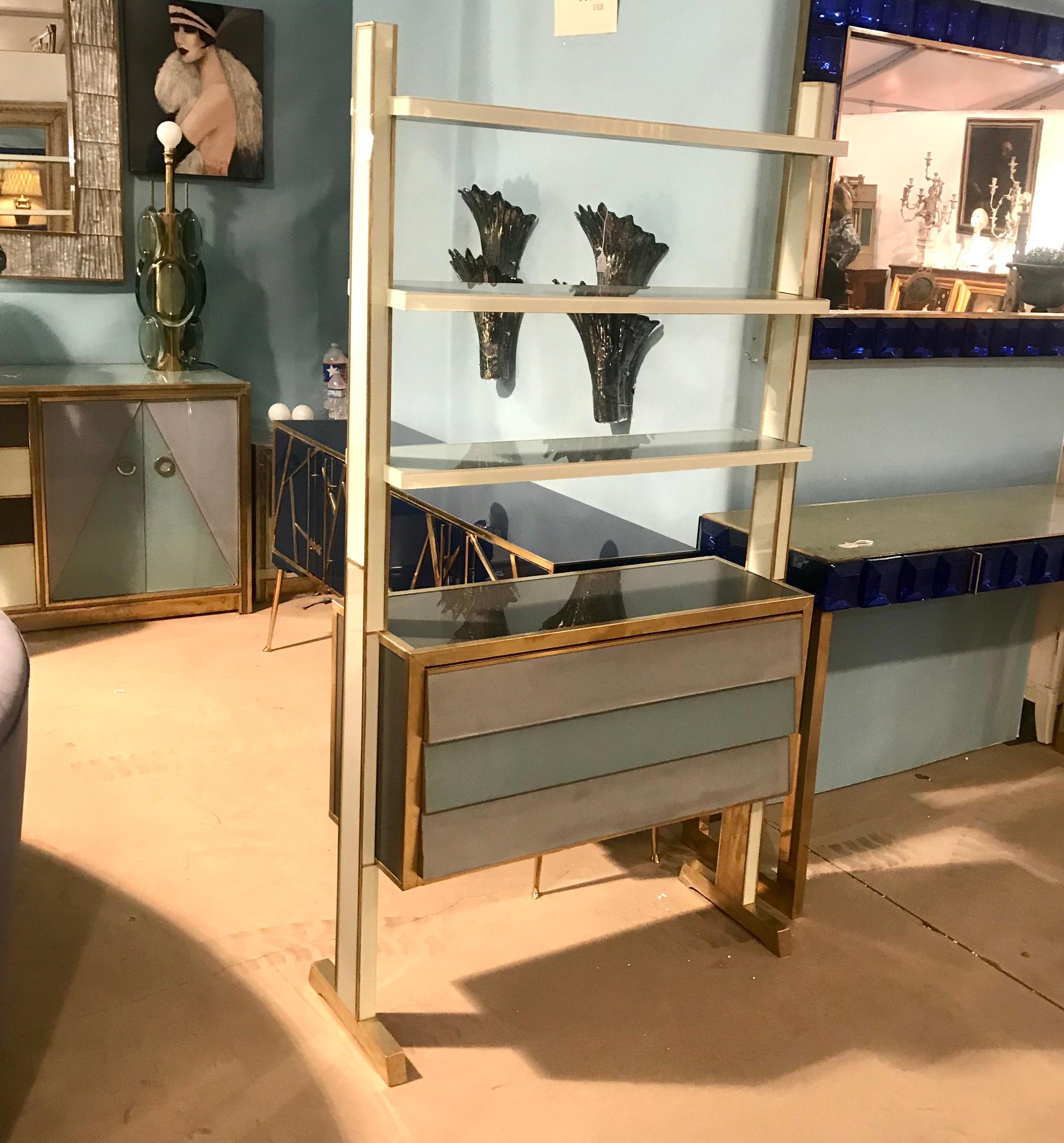 Hues of blue gray reverse painted glass adorn this unique Italian midcentury shelving unit with drawers and brass accents.