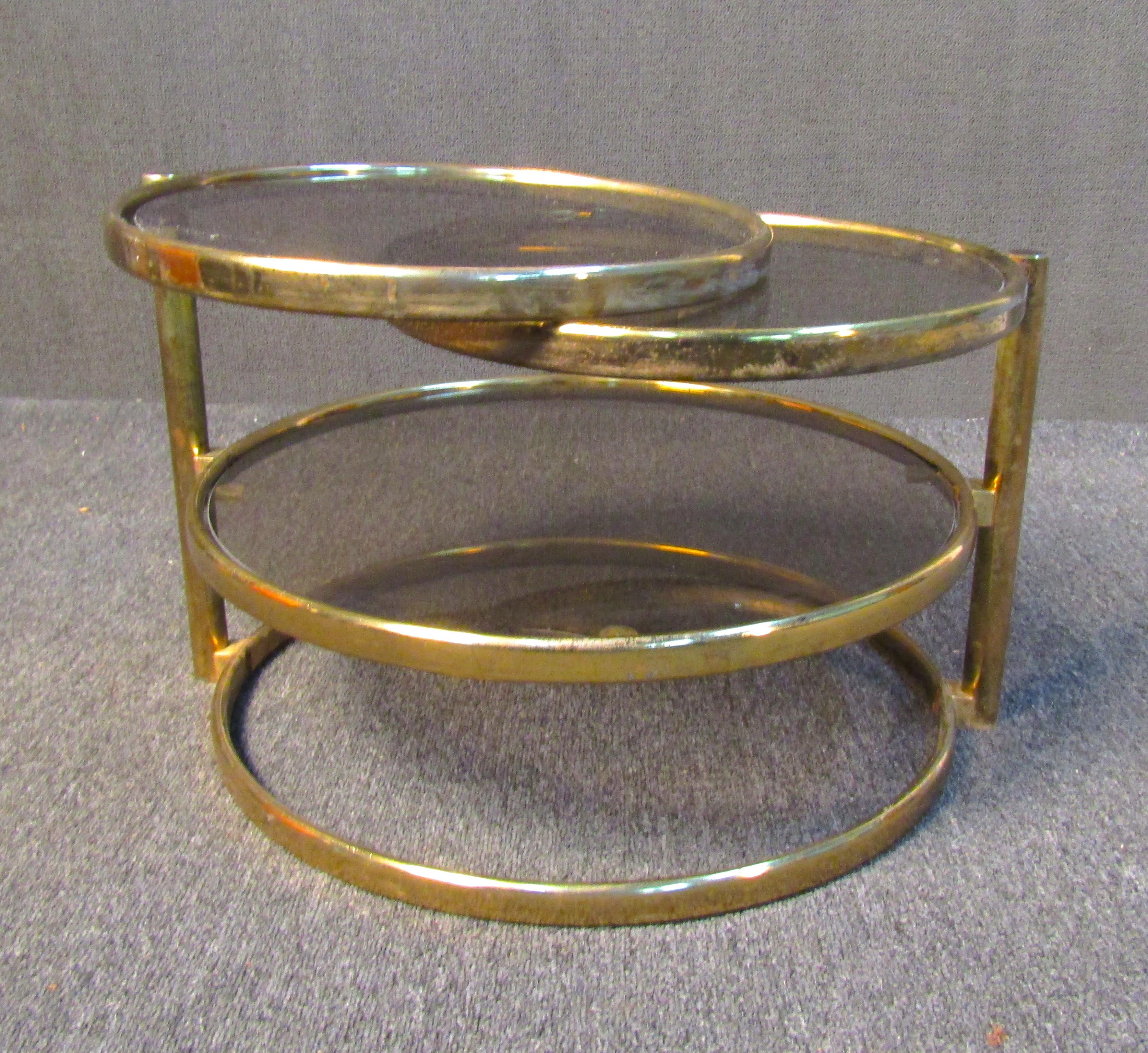 Unique vintage modern side table. The table is comprised of three elegant tiers of glass and brass hoops. The top two tiers can swivel out to expand the table for a variety of uses. This table would make an excellent coffee table, side table, or end