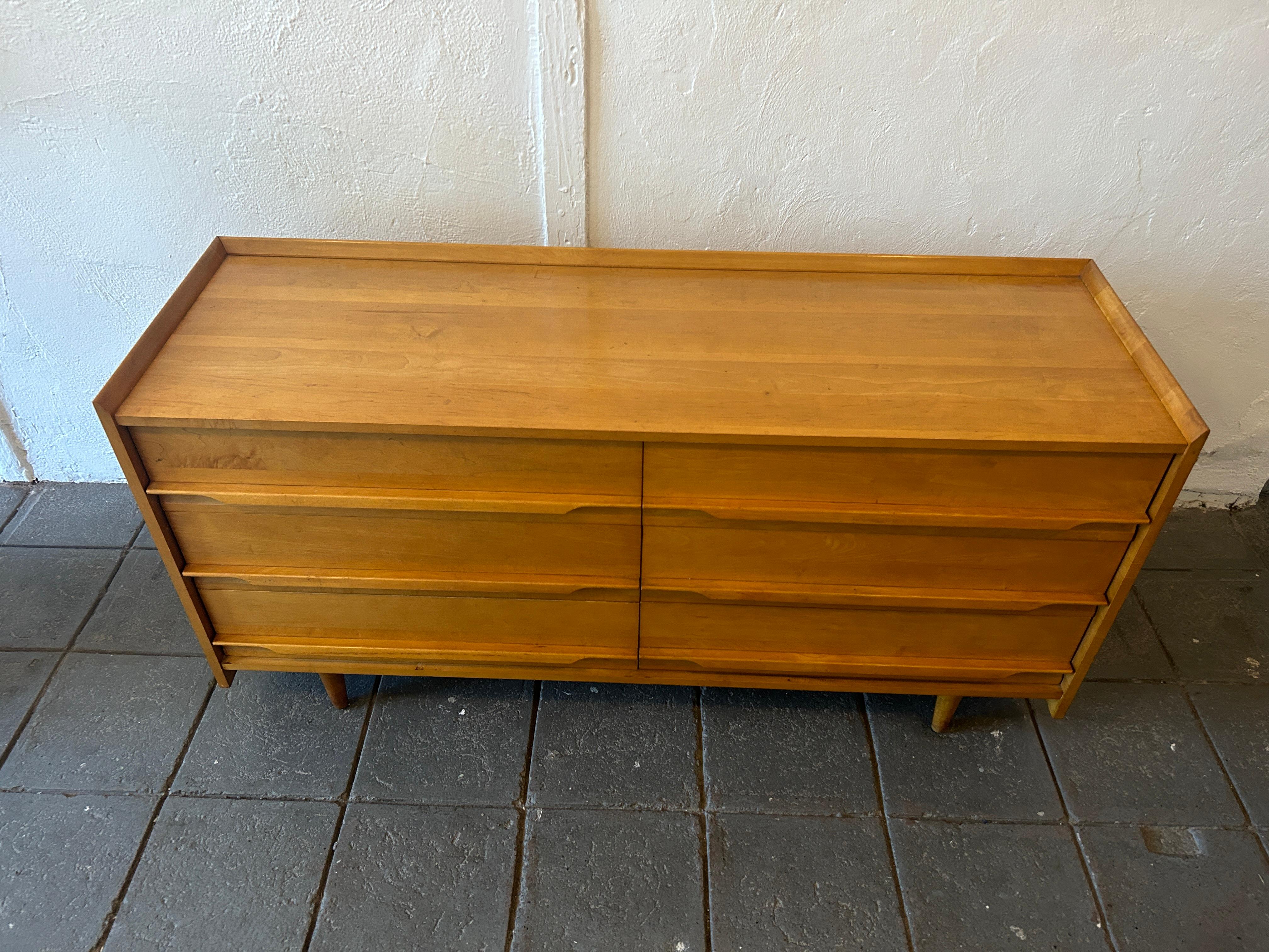 Unique Mid-Century Modern American solid maple 6 drawer low long dresser by Crawford. All solid maple construction with carved handles and sits on 4 tapered legs. Vintage original condition. Shows wear on top surface drawers clean inside. Metal tag