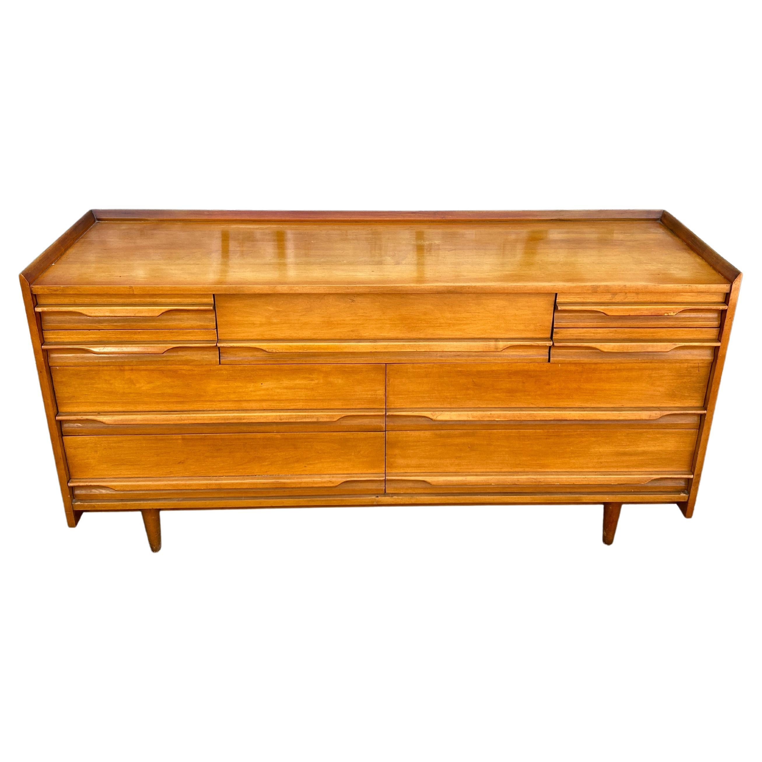 Unique Mid-Century Modern American solid maple tall 9 drawer low long dresser by Crawford. All solid maple construction with carved handles and sits on 4 tapered legs. Vintage original condition. Shows little wear on top surface drawers clean