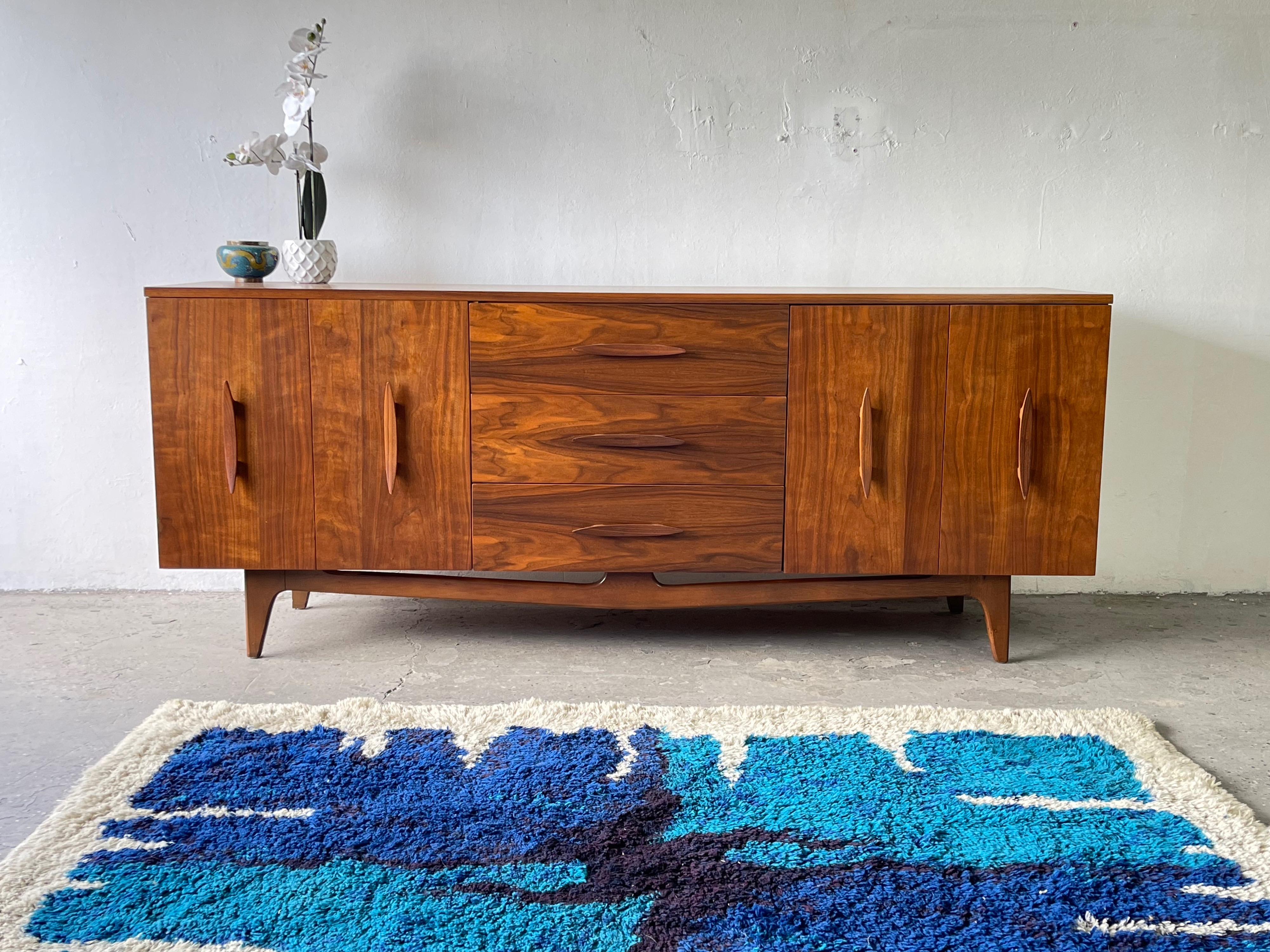 An unbelievably designed Mid-Century Modern credenza/dresser featuring gorgeous carved/ sculpted wood handles! And look at that beautiful wood that has been refinished to bring out that Incredible wood grain. We have a matching Highboy, Nightstands