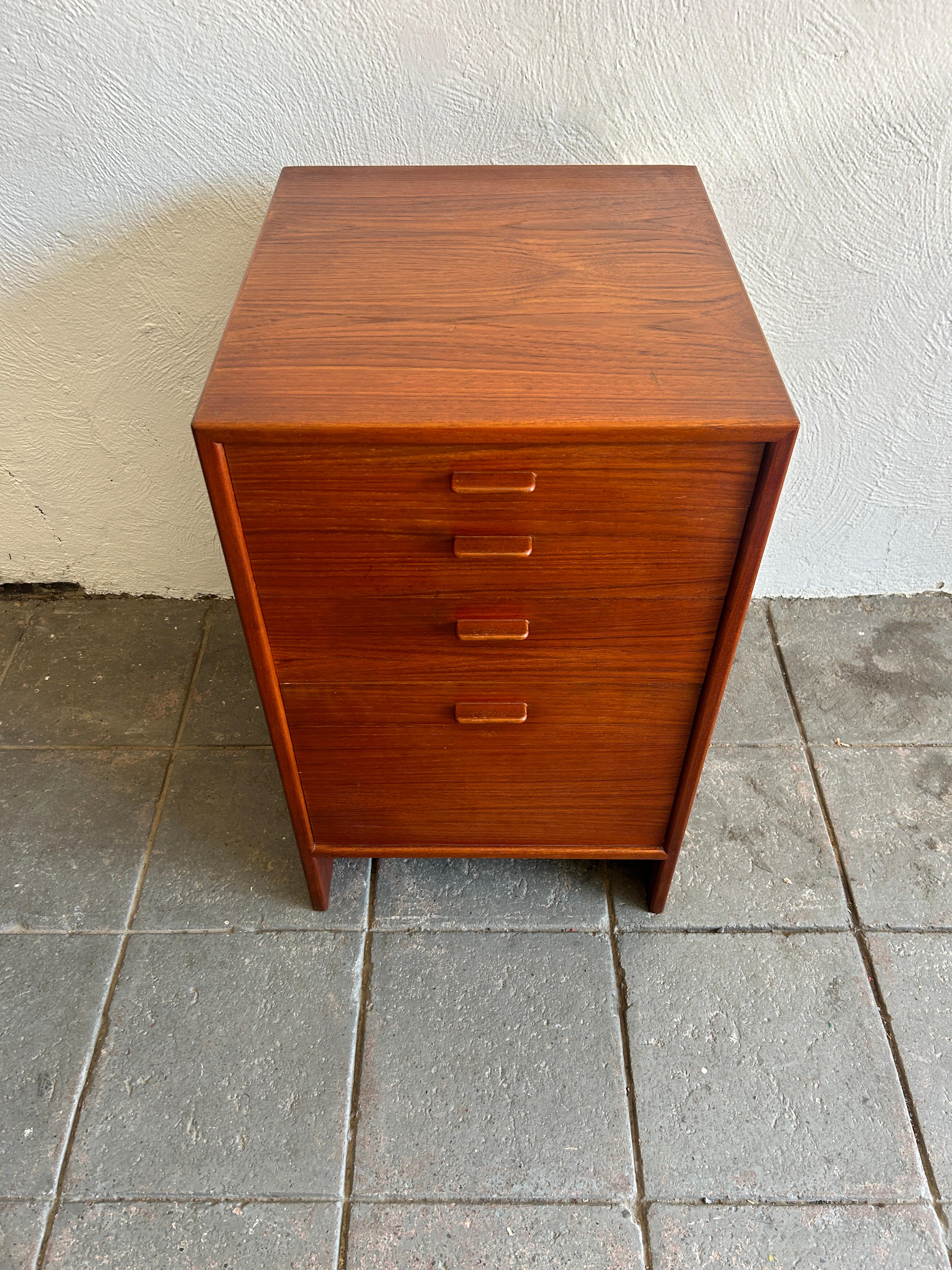 Beautiful Danish teak Narrow 4 drawer dresser or end table designed by Hans J. Wegner Circa 1960. Teak veneer dresser with solid flat teak handles and birch drawer construction. All drawers slide smooth with high end construction. Lower drawer is