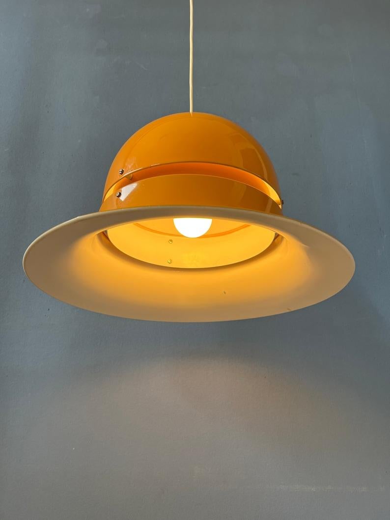 An unique mid century space age pendant light in ocre yellow colour. The lamp is made out of metal and has a glossy yellow lacquer. The lampshade of this pendant lamp is typically spherical or saucer-shaped, resembling a UFO or a futuristic space