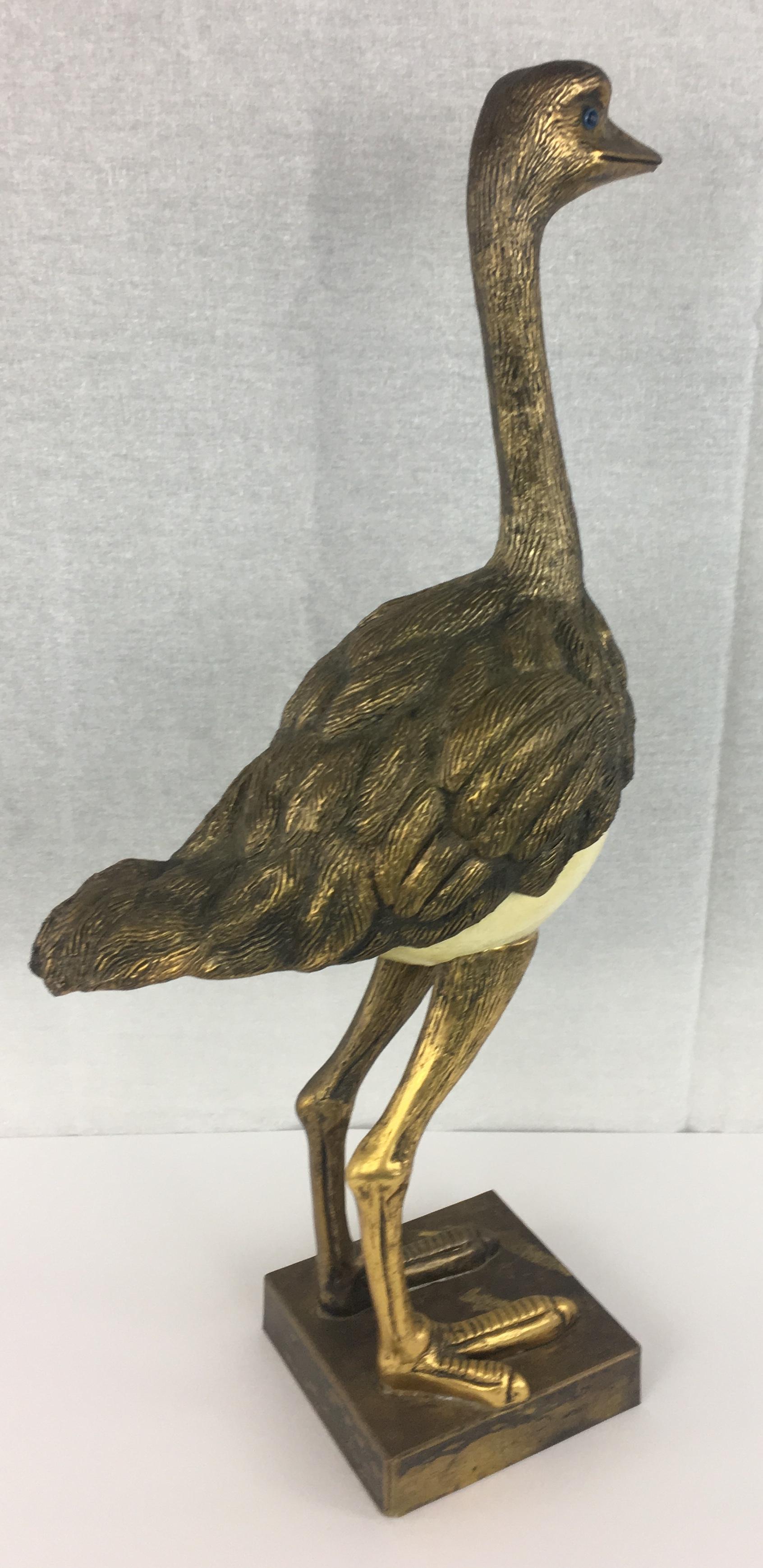 Very decorative mid-century modern sculpture.  Legs, feet, feathered details and head is gold plated metal with glass eyes sculpture resting on a brass base. The details of the sculpted feathers are remarkable.

Designed by Anthony Redmile and