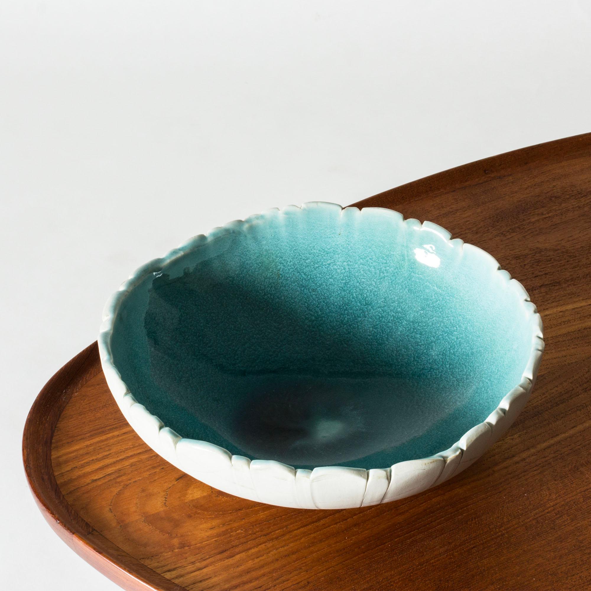 Unique stoneware bowl by Bengt Berglund, in a wide, organic form with an uneven edge. Vibrant aquamarine glazed inside, unglazed outside with an embossed pattern of stripes.