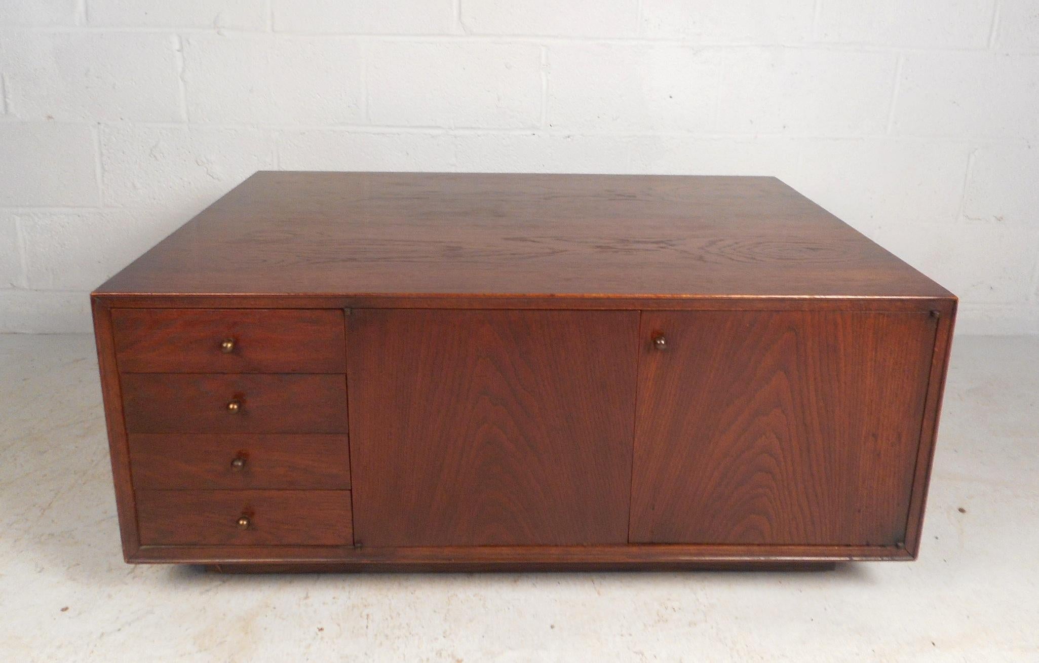 This beautiful vintage modern coffee table features plenty of room for storage within its four drawers and various large compartments. An unusual design that has a finished back with shelves and a large open compartment hidden behind two cabinet