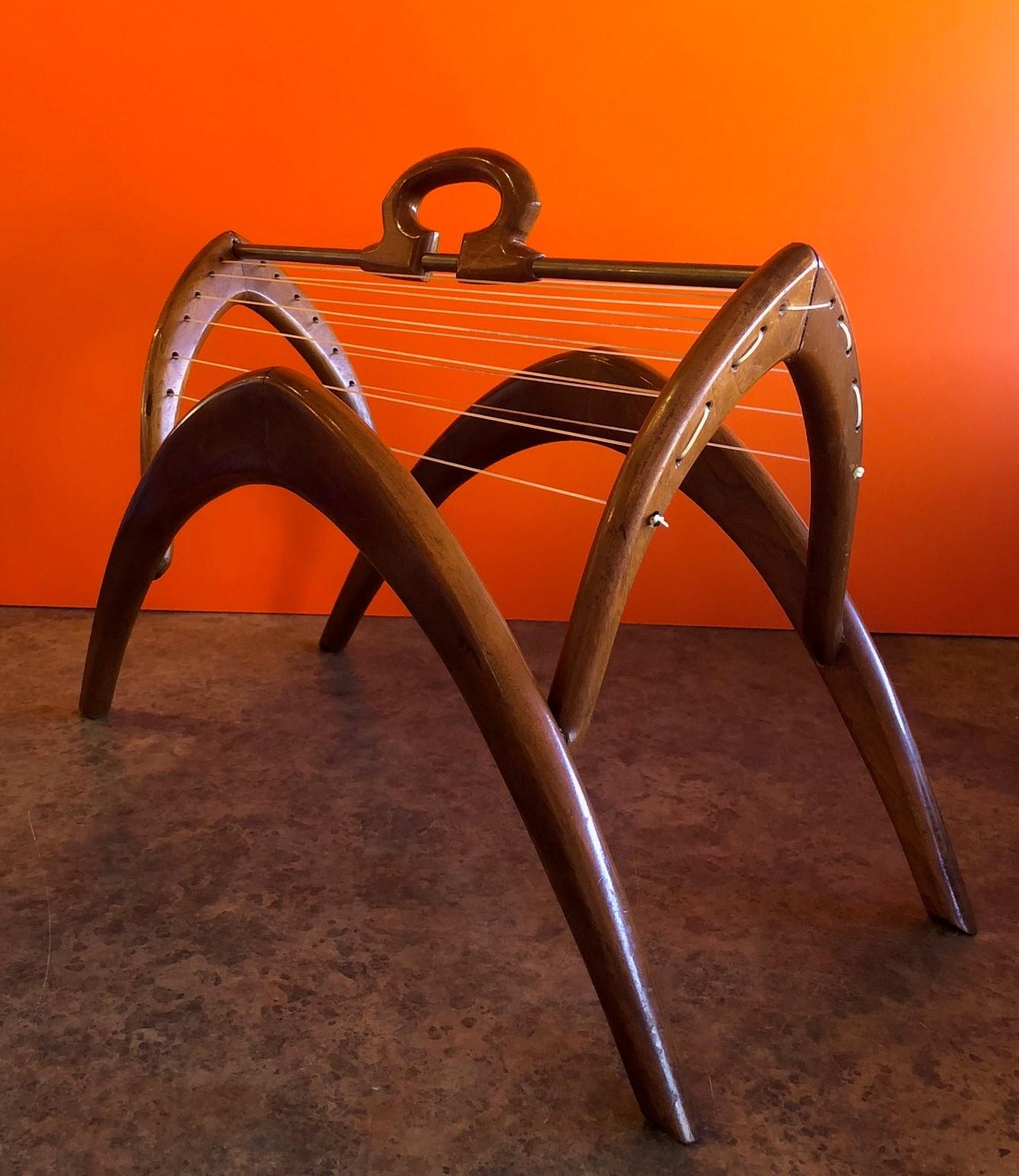 Very unique midcentury walnut / brass / cat gut strings magazine rack, circa 1960s. The piece may be a one off piece as I have not been able to find any information on it. It is very stylish, functional and a very solid well-crafted piece. The