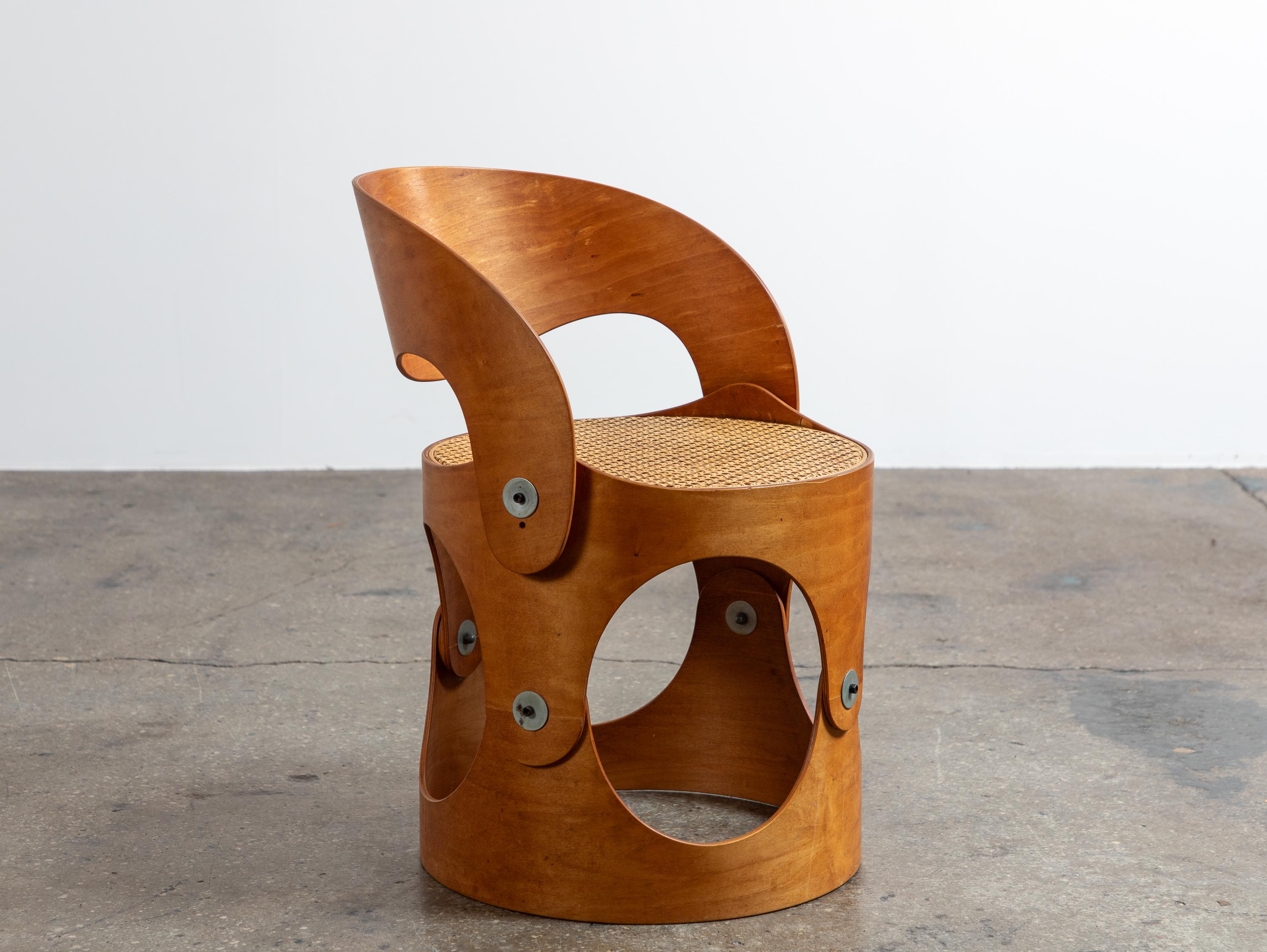 Chaise moderniste en contreplaqué cintré avec assise en cannage tressé, conçue par l'architecte Leandre Poisson. La chaise est composée de structures incurvées en contreplaqué, reliées par des ferrures apparentes et finies par une assise en rotin