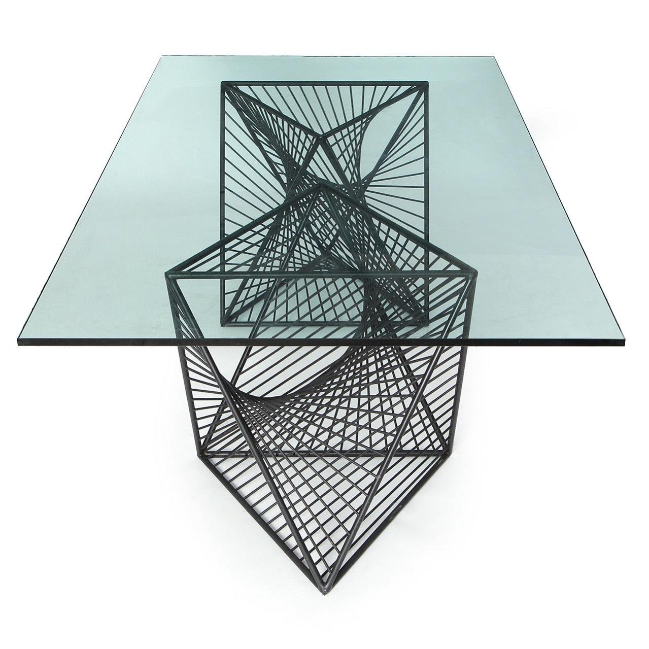 Une table de salle à manger / console expressive et bien dimensionnée. La table présente deux formes géométriques et sculpturales en acier massif, patinées à la main en noir, supportant un épais plateau de verre rectangulaire.