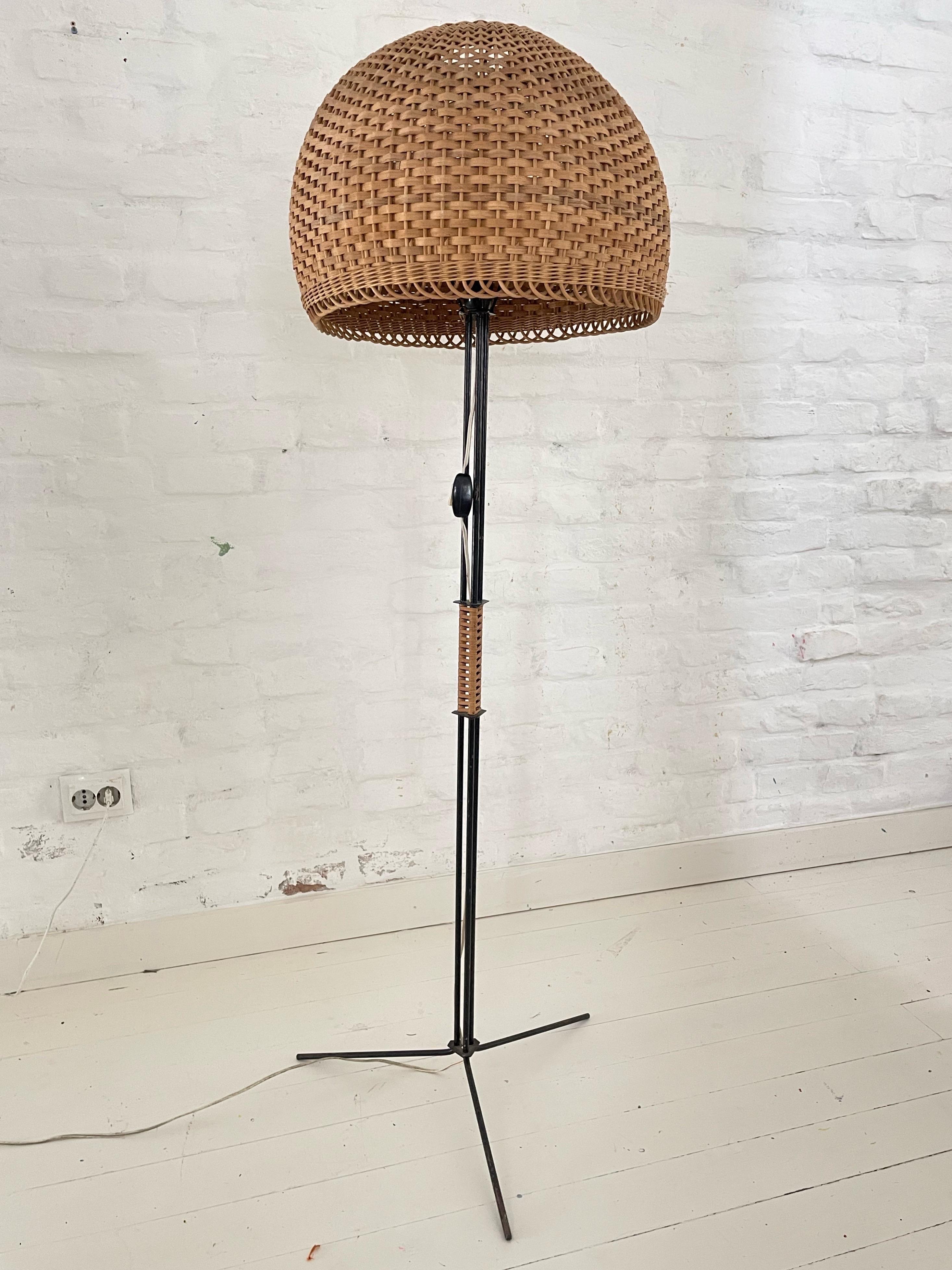 Beautiful Mid-Century Modern tripod floor lamp with basket shade great minimalistic 1950s design. In good vintage condition. The metal frame is painted black and has a wicker wrapped handle. Fully functional with one E27 socket. Works with 220V and