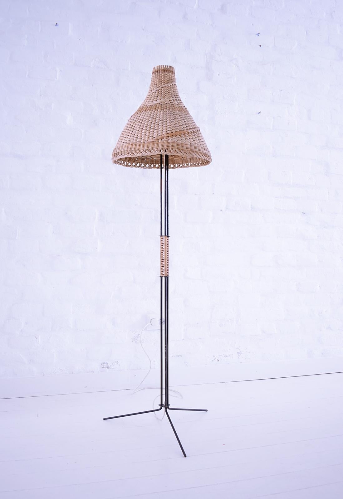 Beautiful Mid-Century Modern tripod floor lamp with basket shade great minimalistic 1950s design. In good vintage condition. The metal frame is painted black and has a wicker wrapped handle. Fully functional with one E27 socket. Works with 220V and