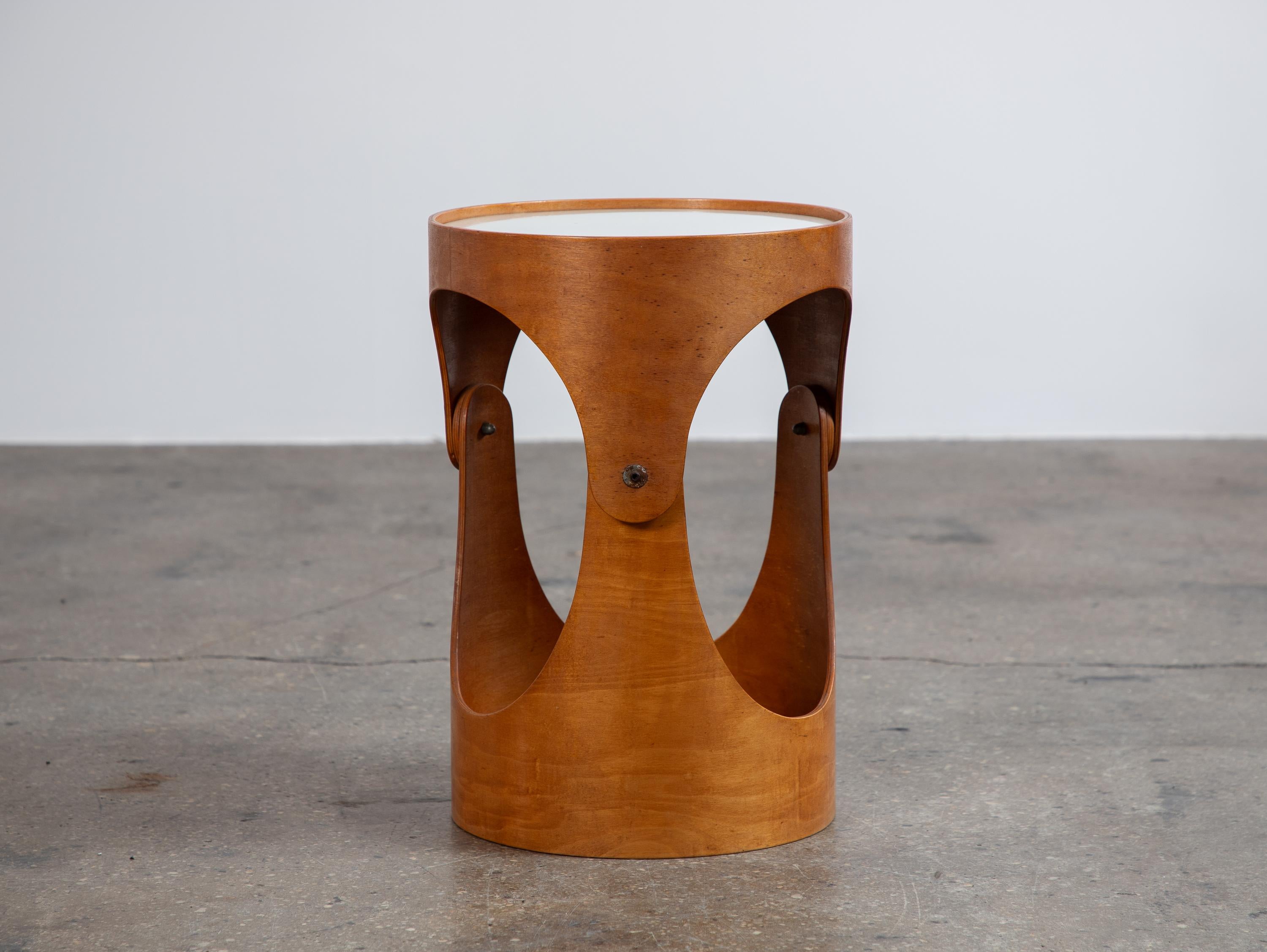 Modernist bent plywood occasional table, designed by architect Leandre Poisson. The table is comprised of a curved plywood base, fitted with an inset white laminate top. This example is one-of-a-kind, acquired alongside a suite of furniture
