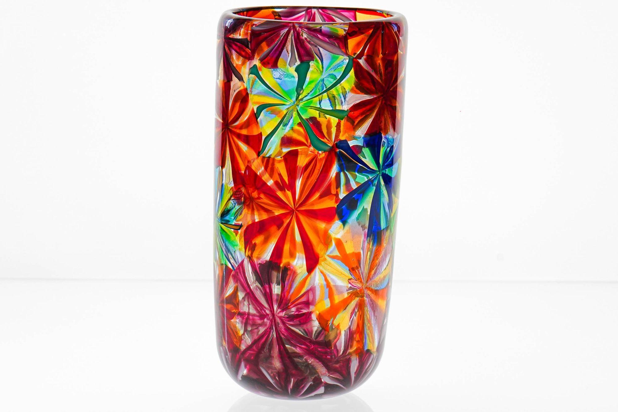 Magnifique vase en mosaïque de Murano avec une parfaite combinaison de couleurs et une technique de mosaïque complexe.

La finition stellato est obtenue en faisant rouler des cannes de différentes couleurs sur un petit bloc de verre incandescent. Le