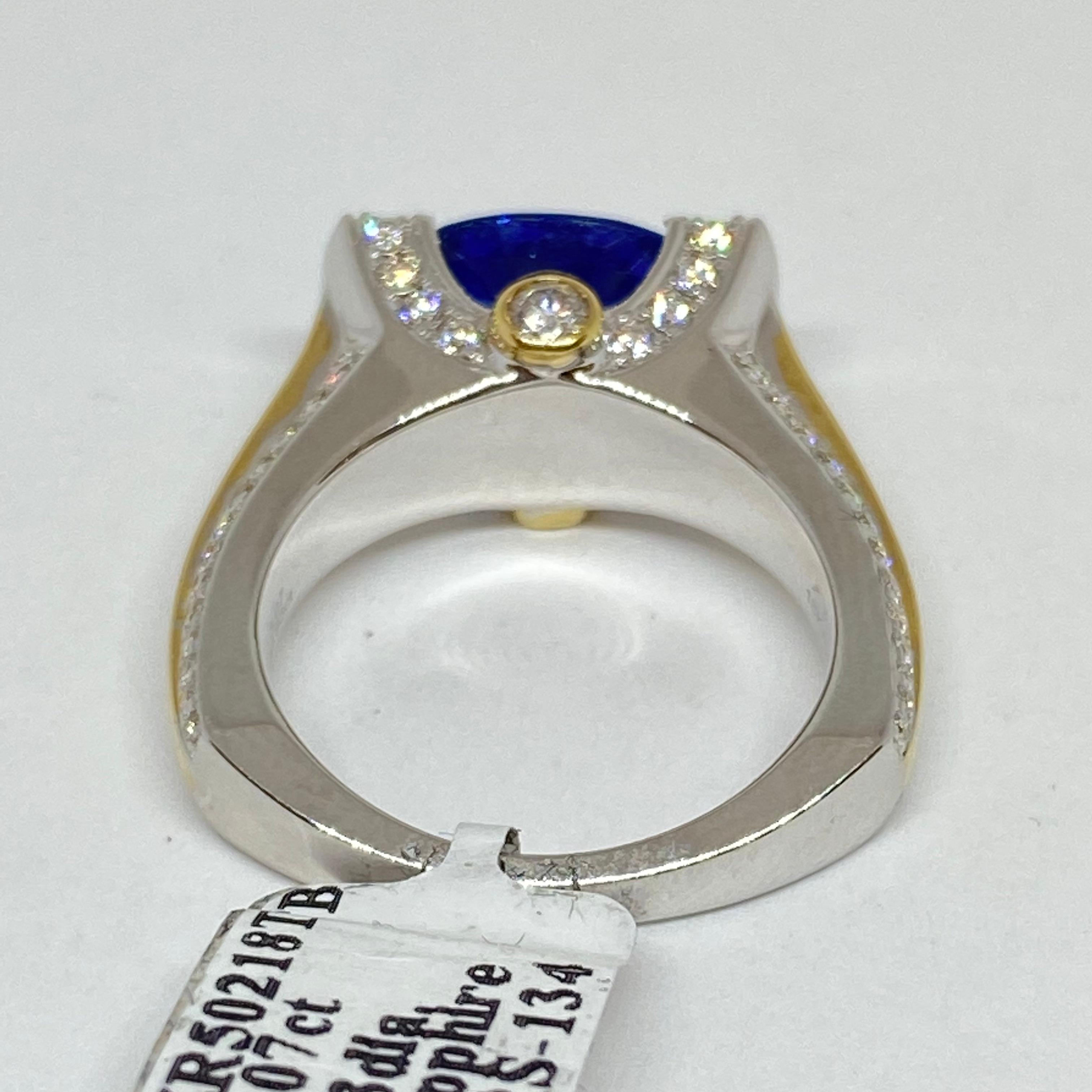 Unique 18 karat two tone mounting set with a natural vibrant blue Sapphire. The sapphire is set east-west in a pave diamond channel tension style mounting, pave diamonds tapering to a square European shank. Bezel and pave set diamonds on the