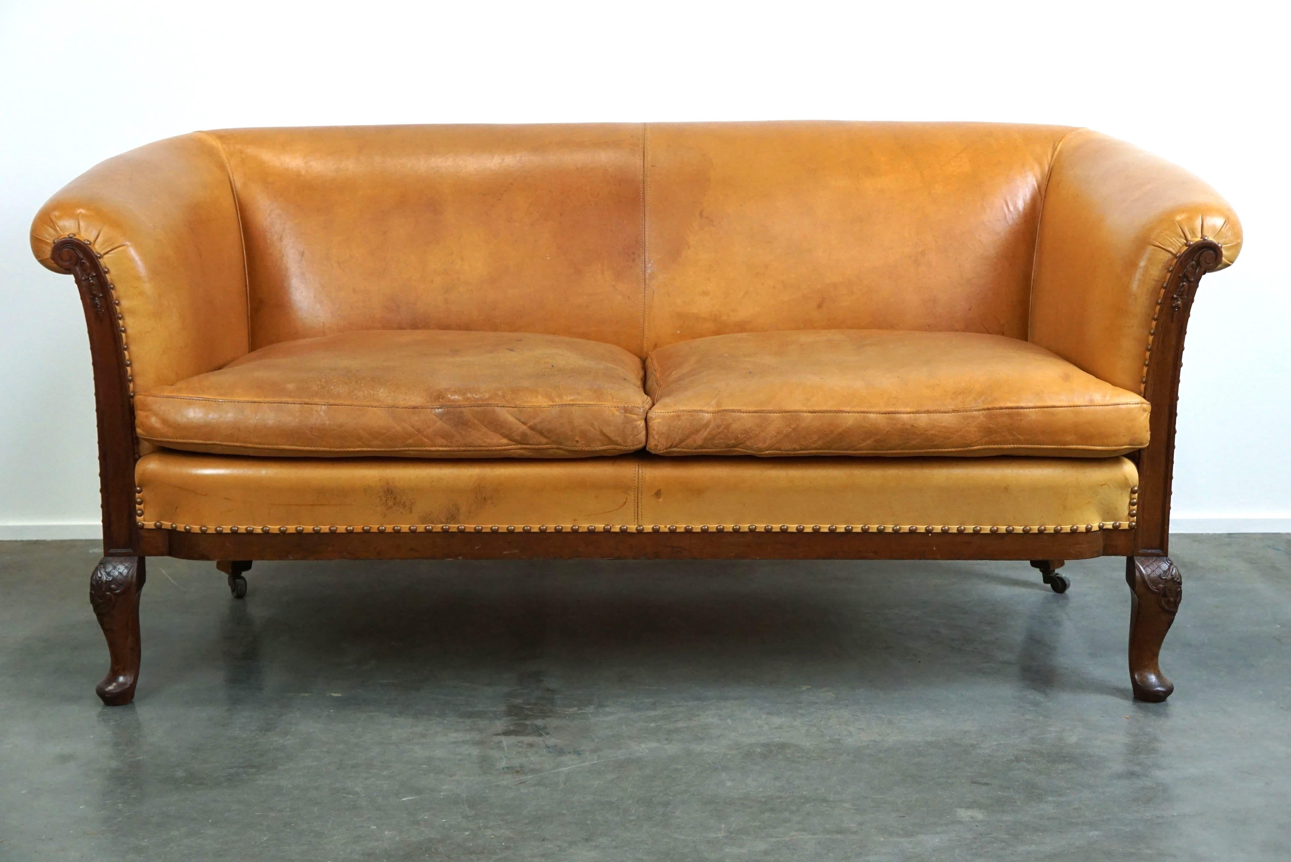 Ensemble unique de deux fauteuils club et d'un canapé en cuir couleur cognac, avec des sculptures en bois, des pieds Queen Anne et des roues sur les pieds arrière.

Une occasion unique pour les passionnés ! Vous voulez un jeu complet ? Alors nous