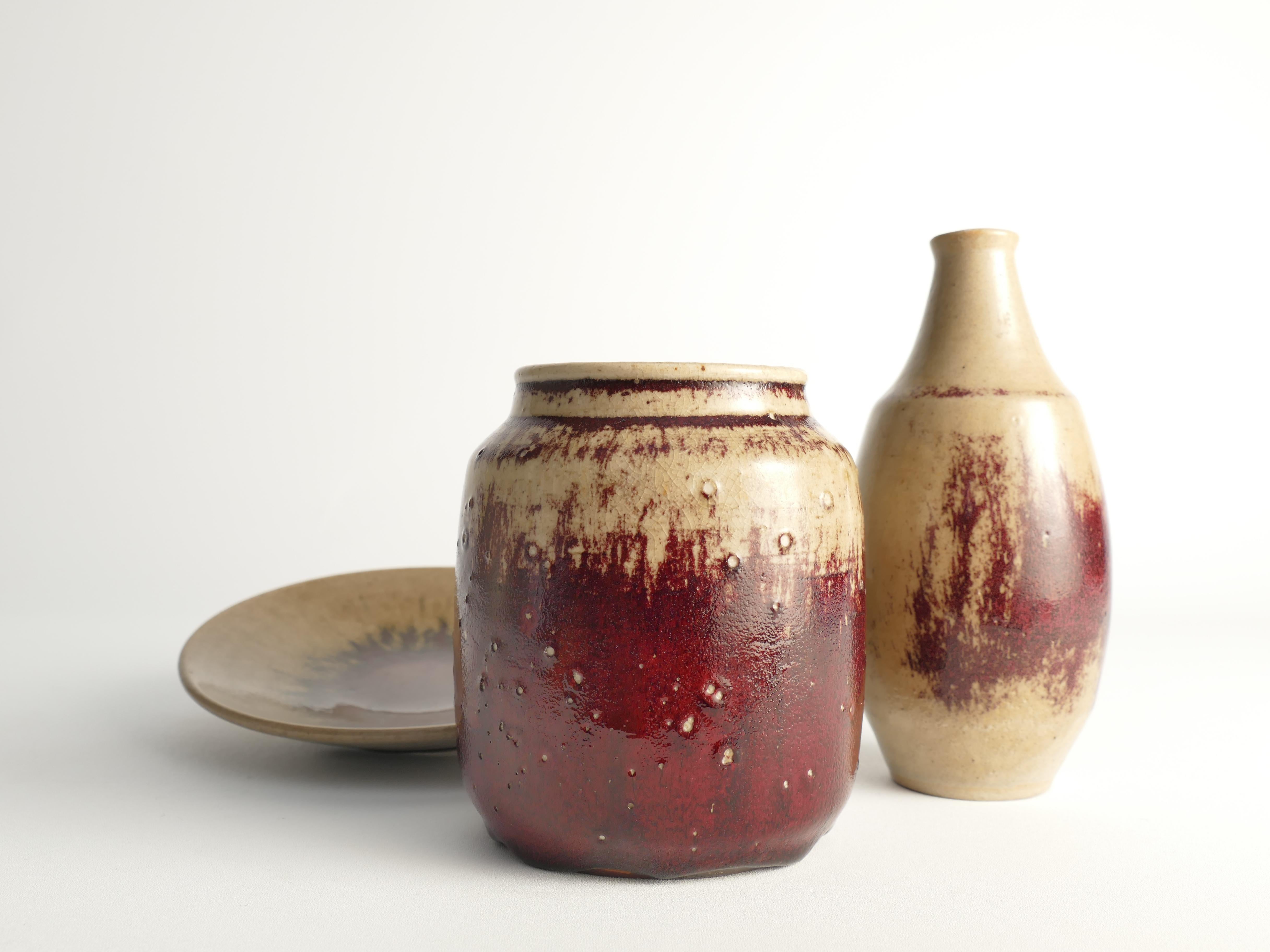Cet ensemble unique en grès se compose d'un vase, d'une jarre et d'une assiette, tous recouverts d'une glaçure sang de bœuf, créés par Henning Nilsson (1907 - 1993) de Höganäs. Chaque pièce porte la signature incisée de Nilsson. 

Le vase, avec sa