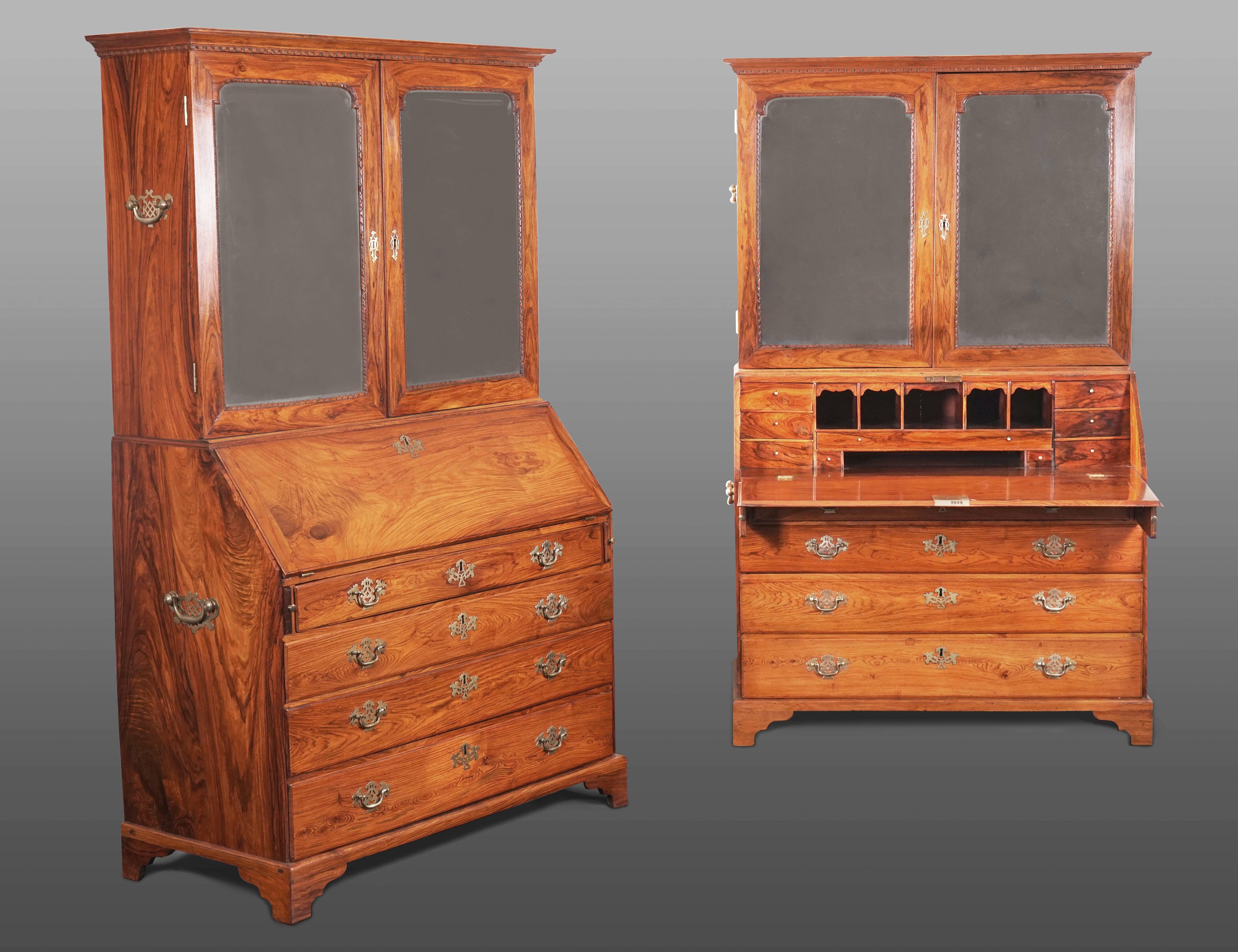 Each rectangular moulded and dentilated cornice above a pair of arched mirror doors with everted corners and leaf carved beaded surrounds enclosing adjustable shelves above two short drawers. The bureau with a fitted interior of six pigeon holes