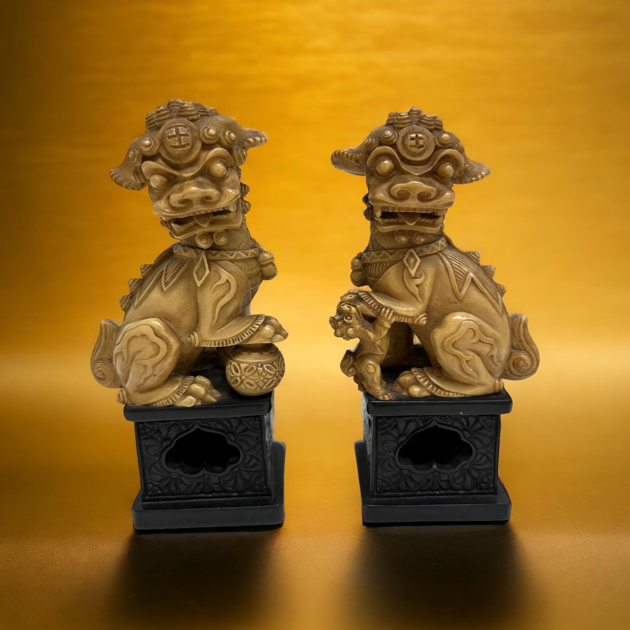 Offered is a pair of Foo Dog sculptures on a black base. These are a classic Asian decorative piece, they are made from soapstone. This type of sculpture typically depicts two guardian lions, one male and one female, standing on a pedestal and said