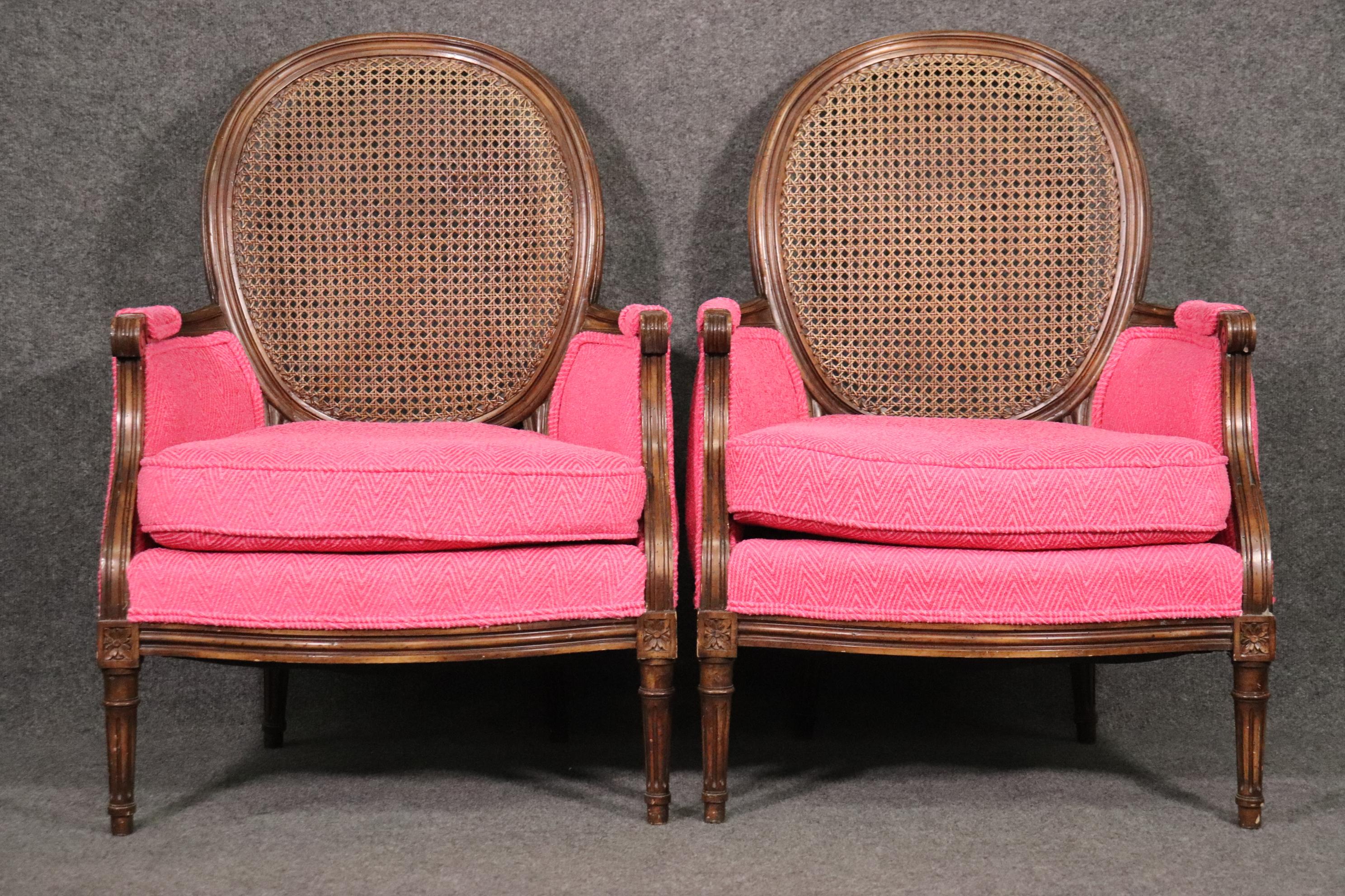 This is a beautiful and unique pair of bergere chairs in walnut with cane backs. The chairs measure 37 tall x 26 wide x 26 deep x seat height of 18. They date to the 1960s era.
