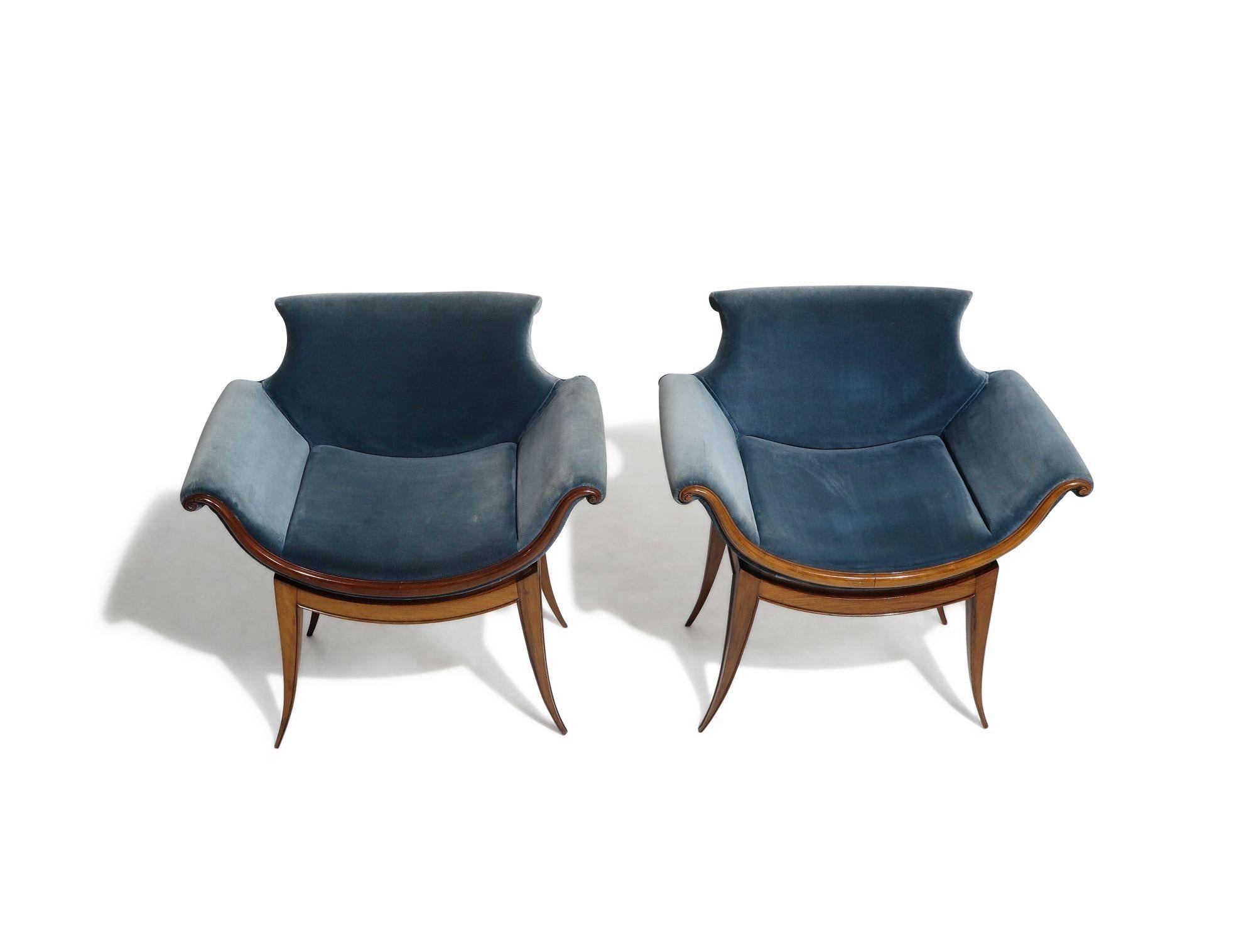 Unique pair of midcentury lounge chairs handcrafted of caviuna wood with dramatic saber legs, upholstered in a vintage blue velvet. 
Good condition with age related wear. 
Measurements 
W 28.50'' x D 23'' x H 29''
Seat height 18''.