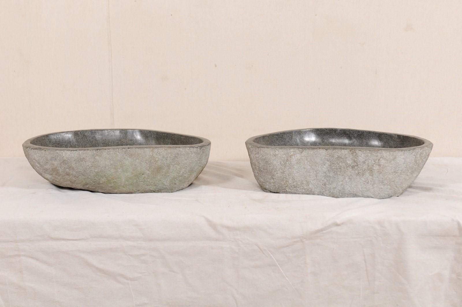 A pair of river rock wash basins. This pair of sinks have each been carved from a single, natural river rock boulder. Each sink has a polished bowl with natural stone on the exterior. Beautifully organic designs courtesy of Mother Nature, no two
