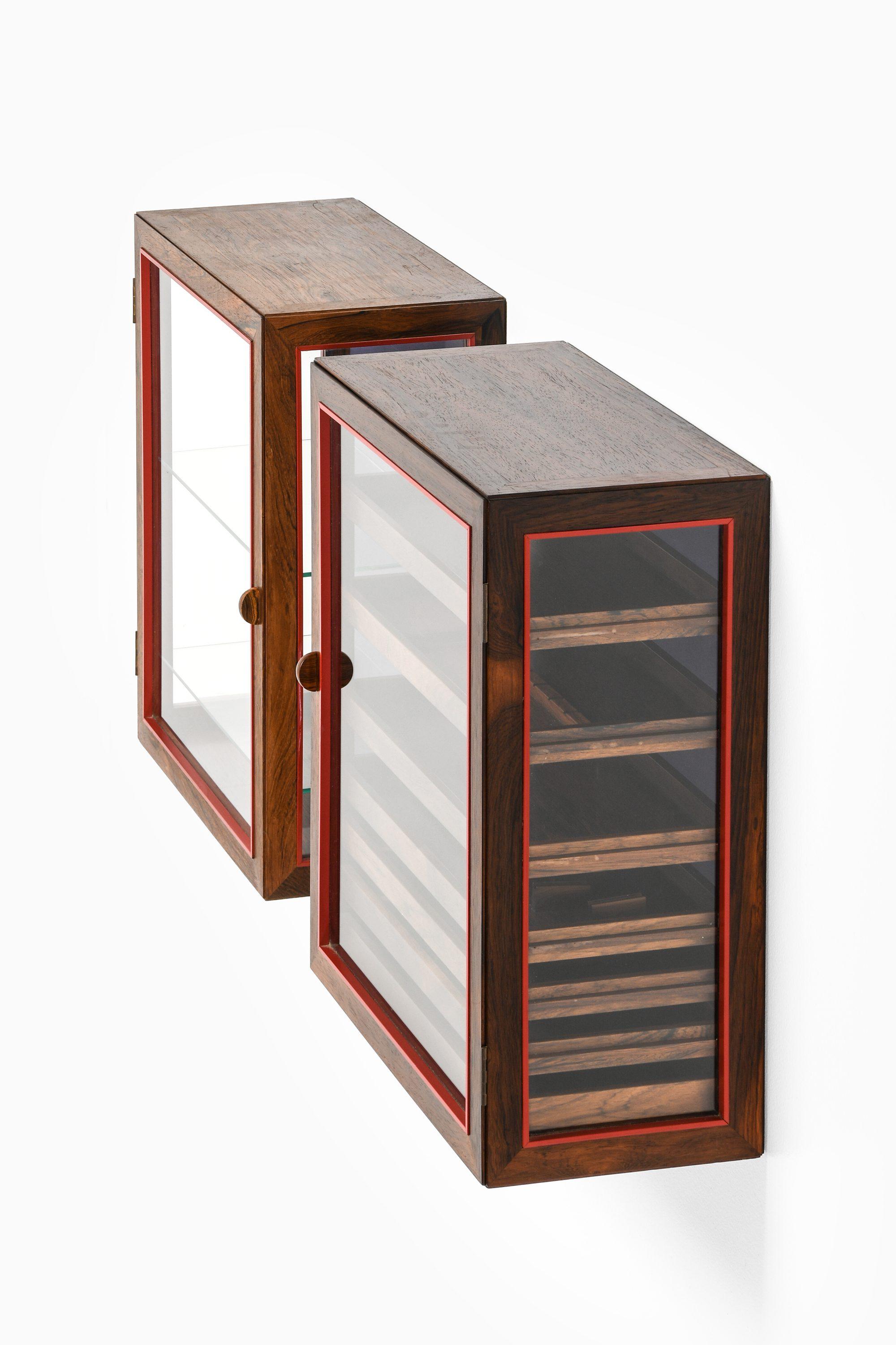 Pair of Wall Mounted Cabinets in Rosewood, Glass and Brass by Poul Østergaard

Front and sides with red profiles and brass fittings. Interior with blue fabric backside, one cabinet with seven pull-out cutlery trays of Brazilian rosewood, other
