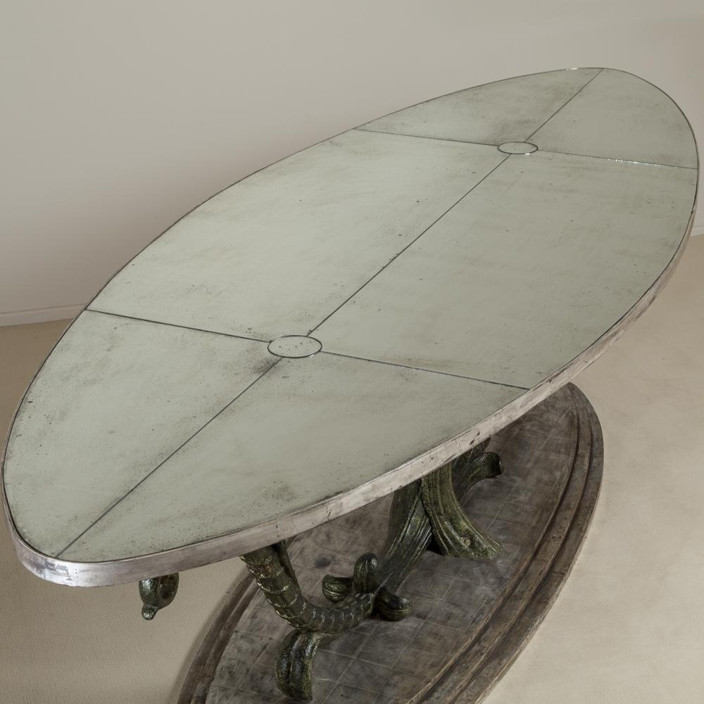 A large unique cast iron centre table made from 19th century scrolling acanthus cast iron pieces set on an oval stepped silverleafed base with an oval antiqued mirror top

The table top has two circular cutouts to allow lamps to be sat ontop and the