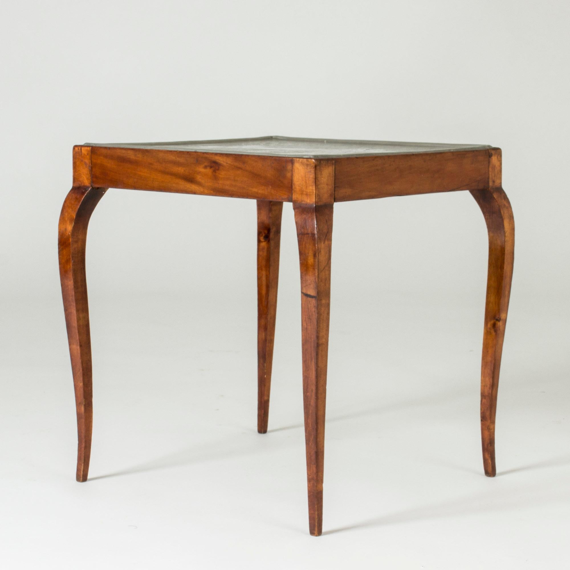 Stunning side table by Anna Petrus, made in her own workshop in 1925. Neat wood frame with sleek, curved legs. Pewter table top depicting a beautiful outside scene, with a stream, an apple tree and animals. A small child offers an apple to a woman