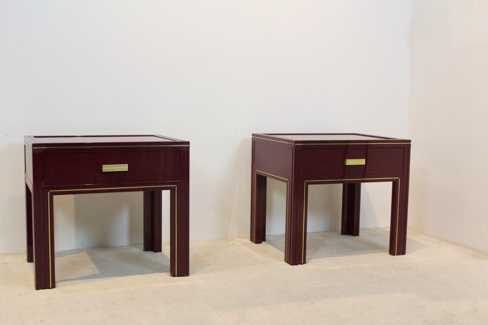 Unique Pierre Vandel Paris Burgundy Lacquered French set of sidetables or nightstands made from aluminum and glass. In burgundy aluminum with beautiful Gold accents. Featuring one drawers and glass tier. With some light wear due to age and use.