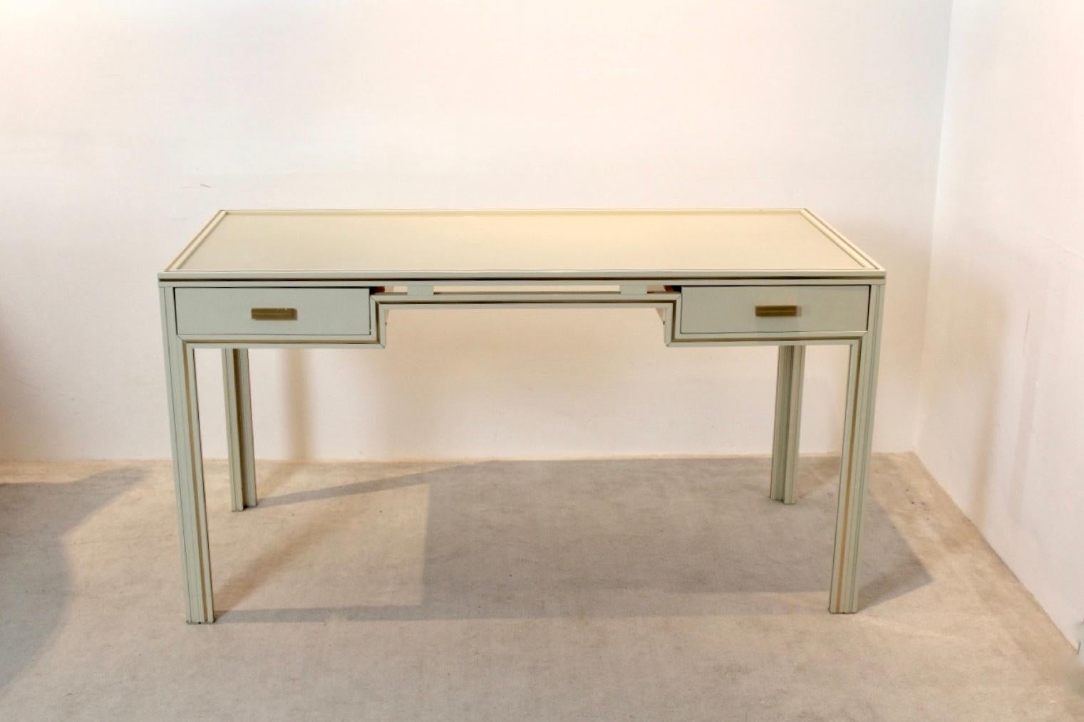 Unique Pierre Vandel Paris cream lacquered French desk made from aluminum and glass. In cream aluminium with beautiful Gold accents. Featuring two drawers and glass tier. With some light wear due to age and use. Pierre Vandel was a French interior