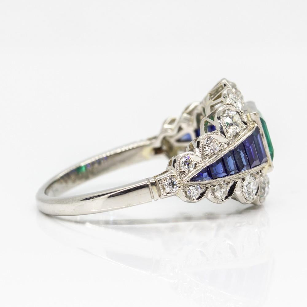 This drop-dead gorgeous ring is centered with one natural square cut calibrated Colombian emerald that weighs 1.05ctw.
At both sides of the central flawless stone, the ring showcases 6 natural calibrated cut sapphires that weigh 1.10ctw. (2.20ctw