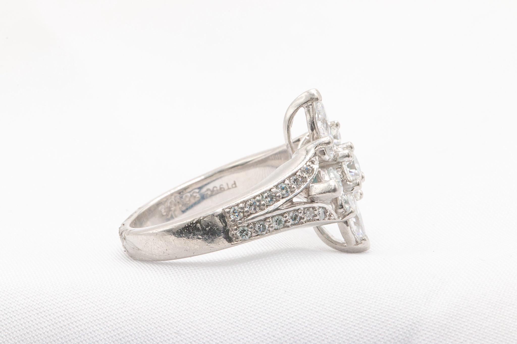 Questo anello di diamanti a fiore in platino, unico nel suo genere, è un pezzo straordinario con un delicato disegno floreale. Misura 5,75 e realizzato in platino, l'anello contiene un peso totale stimato di 1,65 carati, con un diamante centrale di