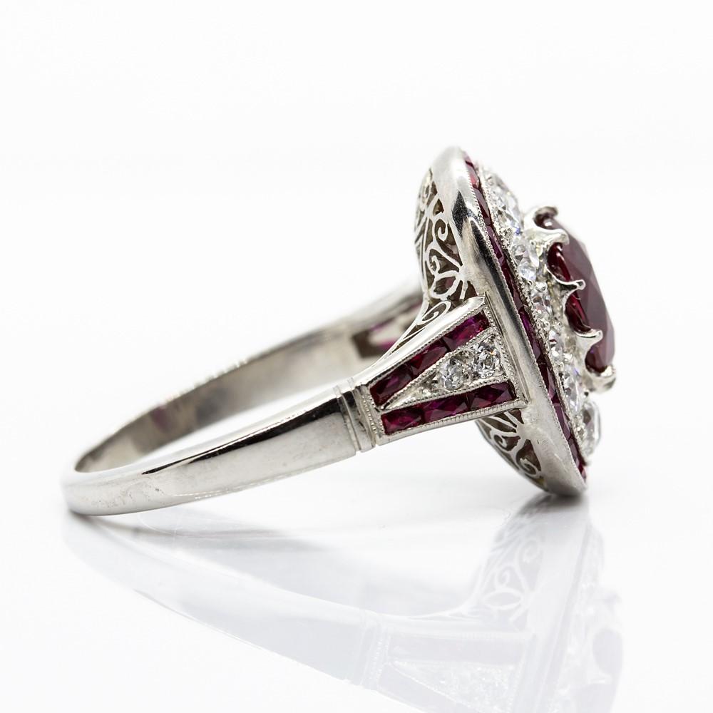This exquisite piece of jewelry holds one Gia Certified natural cushion cut ruby that weighs 2.19ctw (Report Number 6194829142).
The central stone is framed with 18 old mine cut diamonds of H-VS2 quality that weigh 1ctw.
Crafted in platinum, this