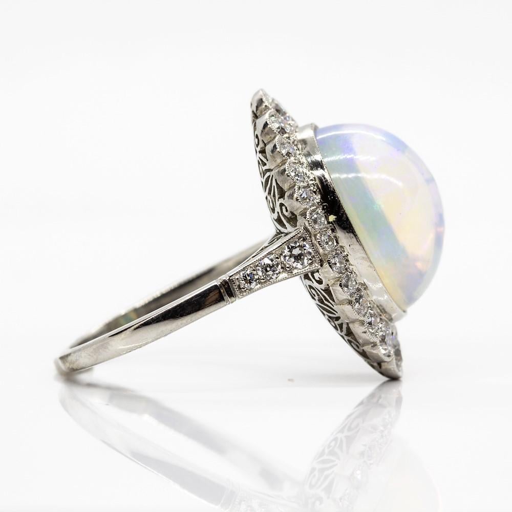 This exquisite item showcases a flawless natural opal that measures 20mm by 11mm.
Crafted in solid platinum, this lovely piece of jewelry is embellished with 28 old mine cut diamonds that weigh 1ctw.
Ring size 7 ½  (Resizing available)
Total weight: